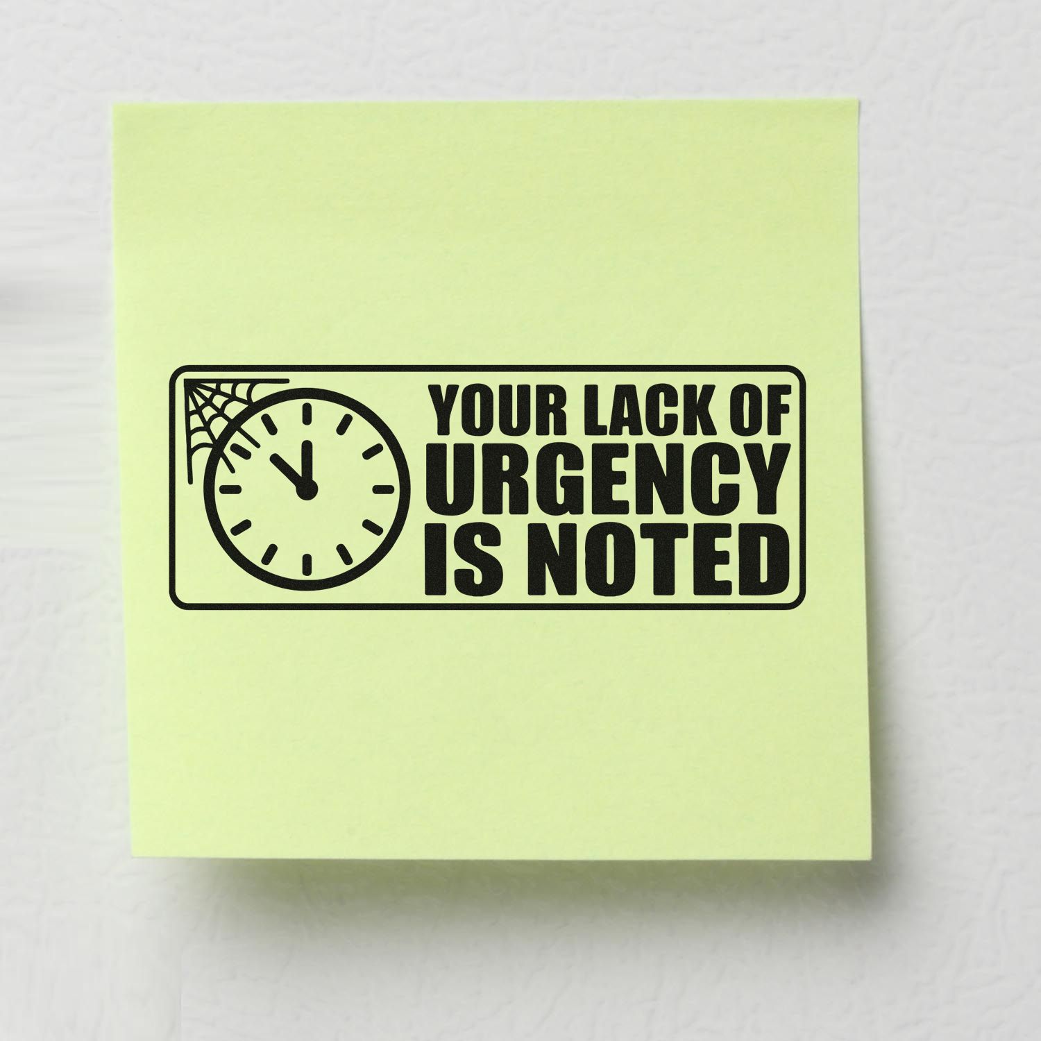 Black rubber stamp seal with clock and spider web graphic on pale yellow paper, reading Your lack of urgency is noted.