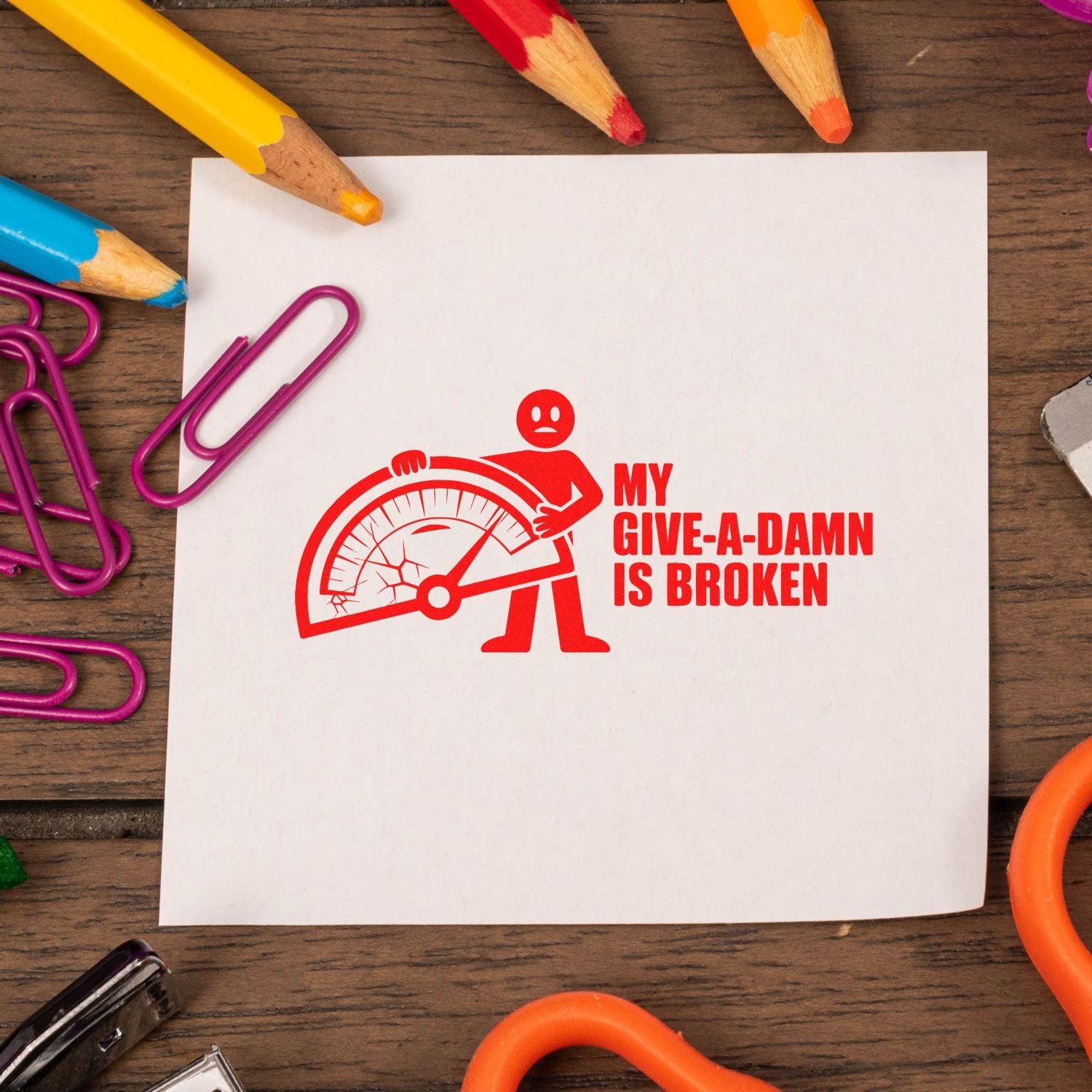Red self-inking stamp and seal reading My give-a-damn is broken with sad figure and broken gauge on white paper.