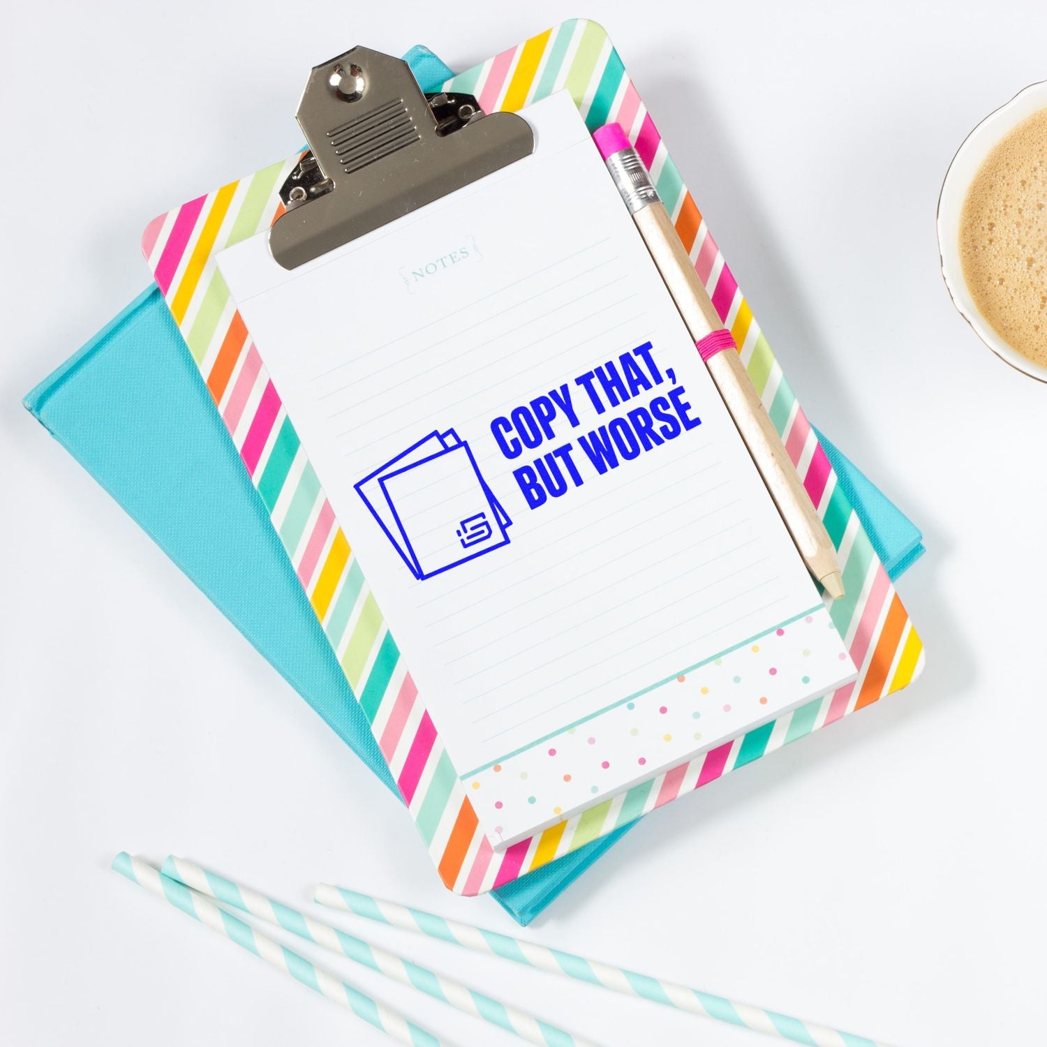 Blue custom stamp/seal imprint on lined notepad, clipped to colorful striped clipboard with pencil and turquoise folder.