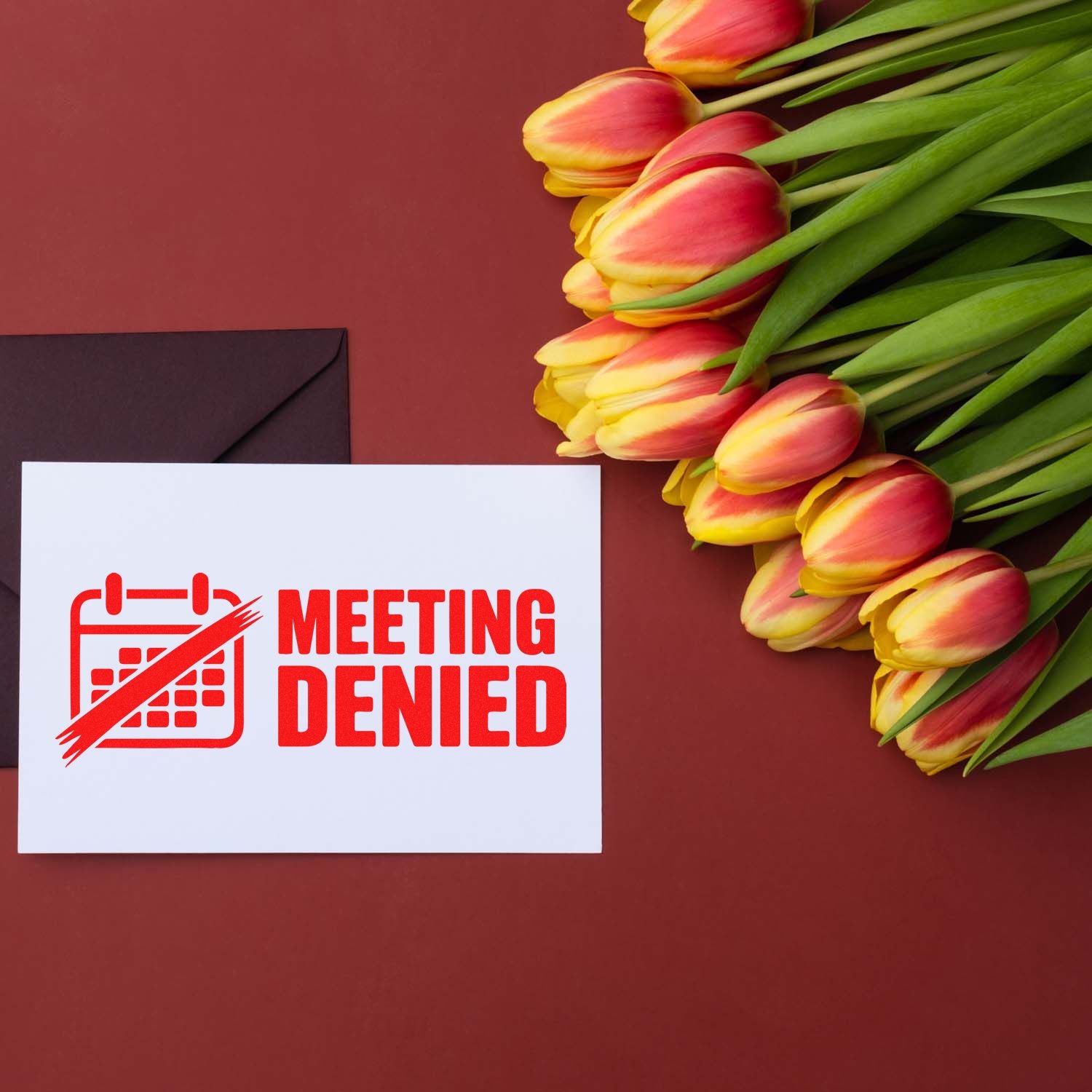 Red Meeting Denied stamp and seal on white card beside black envelope and pink-yellow tulips on burgundy background.