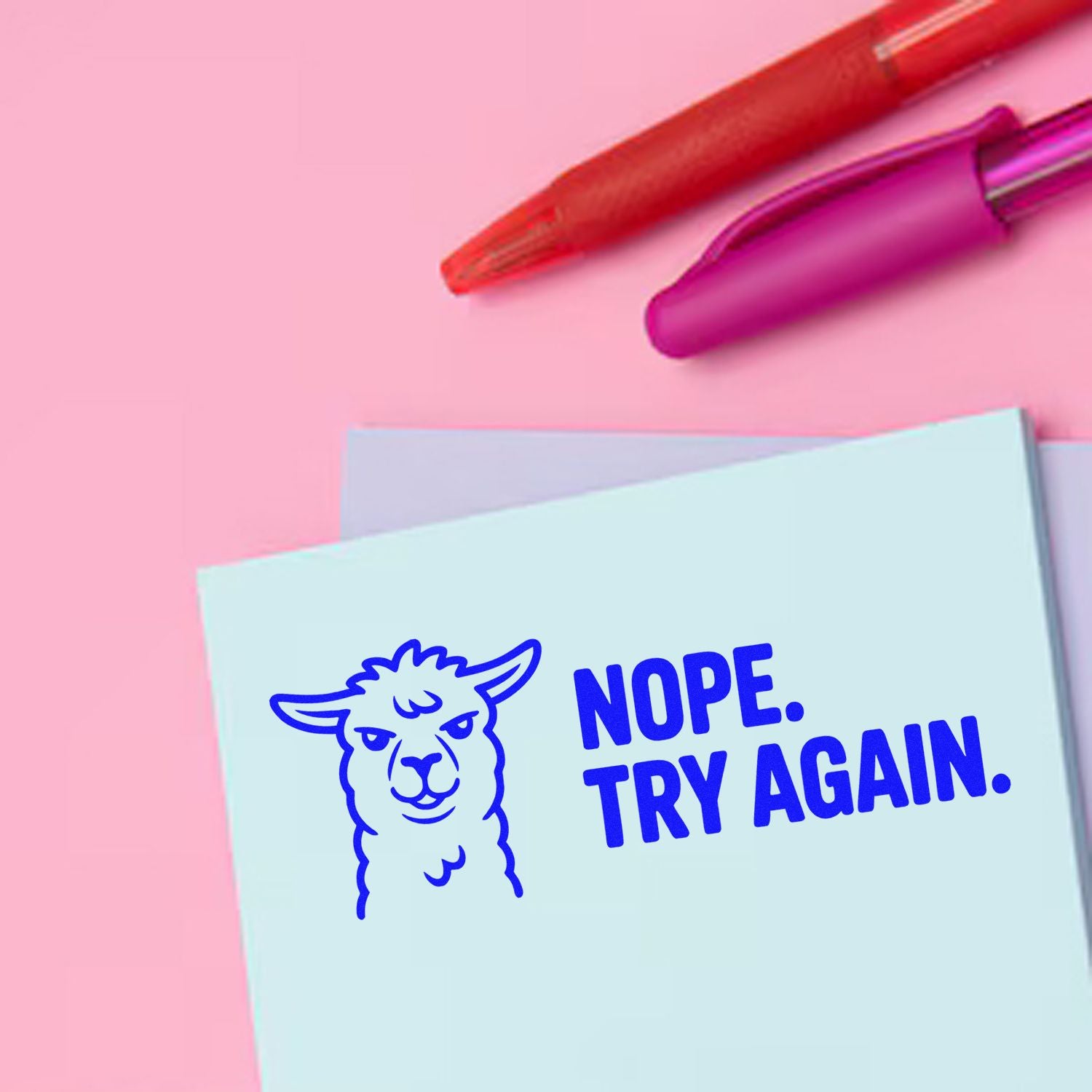 Red and magenta stamp pens on pink background above a blue llama seal reading NOPE. TRY AGAIN.