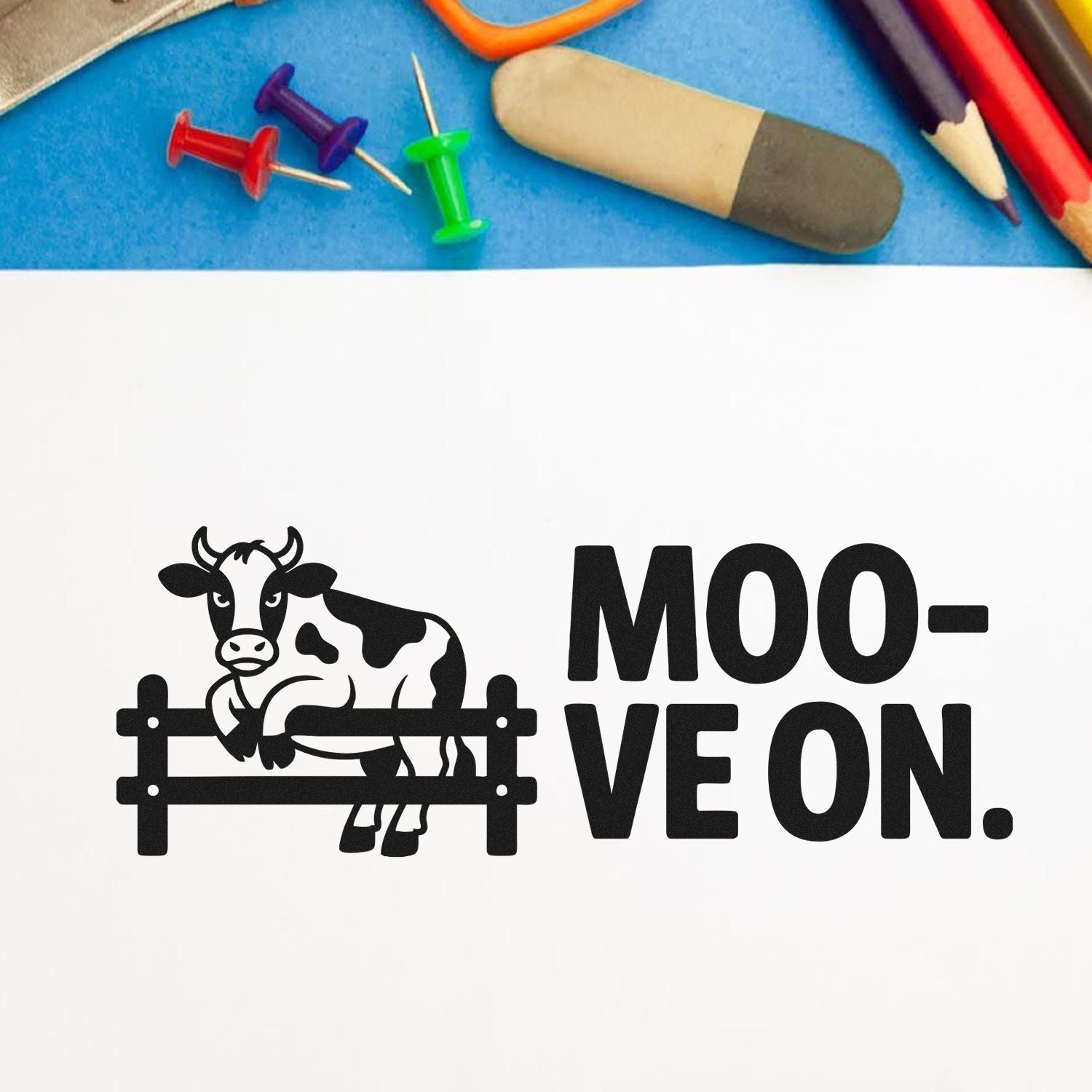 Black cow fence stamp design with MOO-VE ON. text, beside colorful pencils, push pins, and eraser on blue.