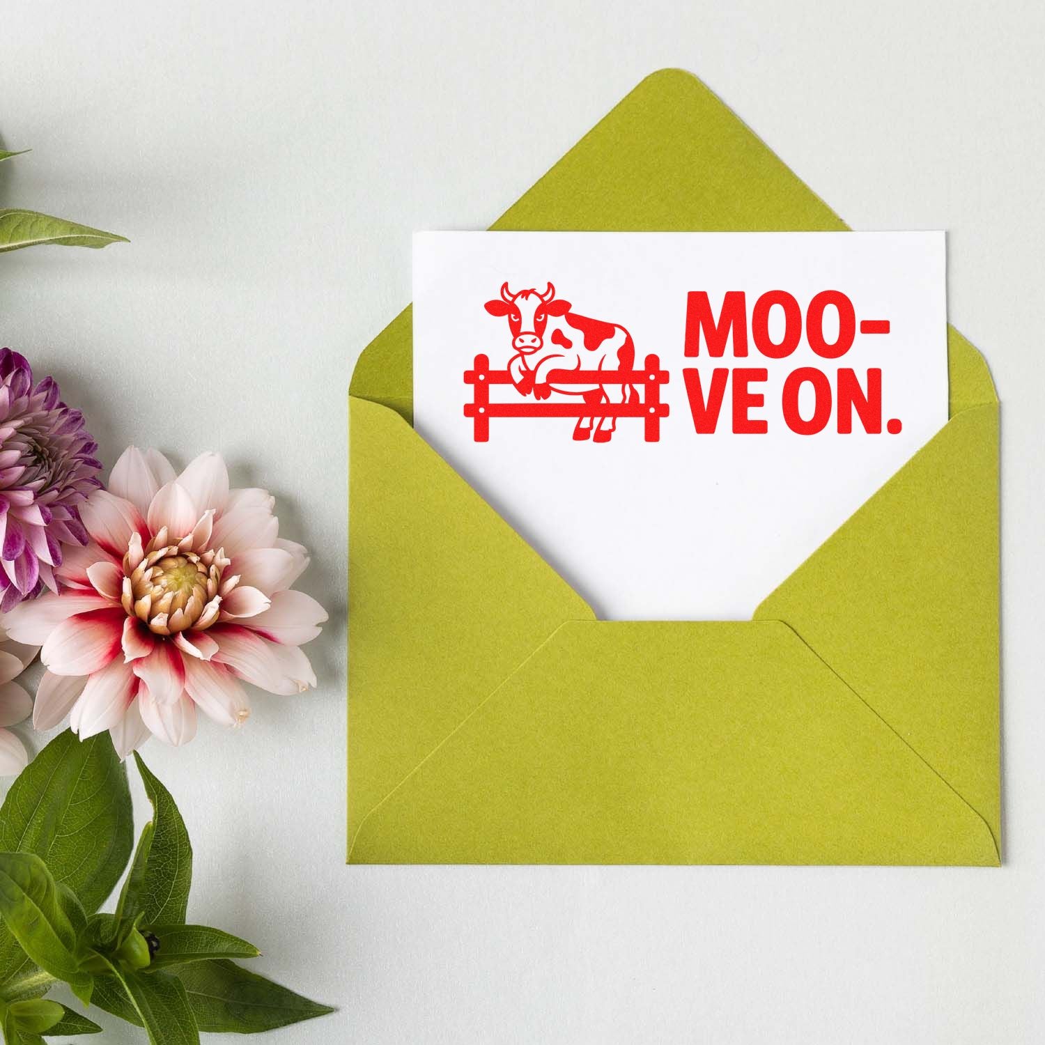 Red cow stamp seal on white card in lime green envelope, with MOO-VE ON text and flowers.
