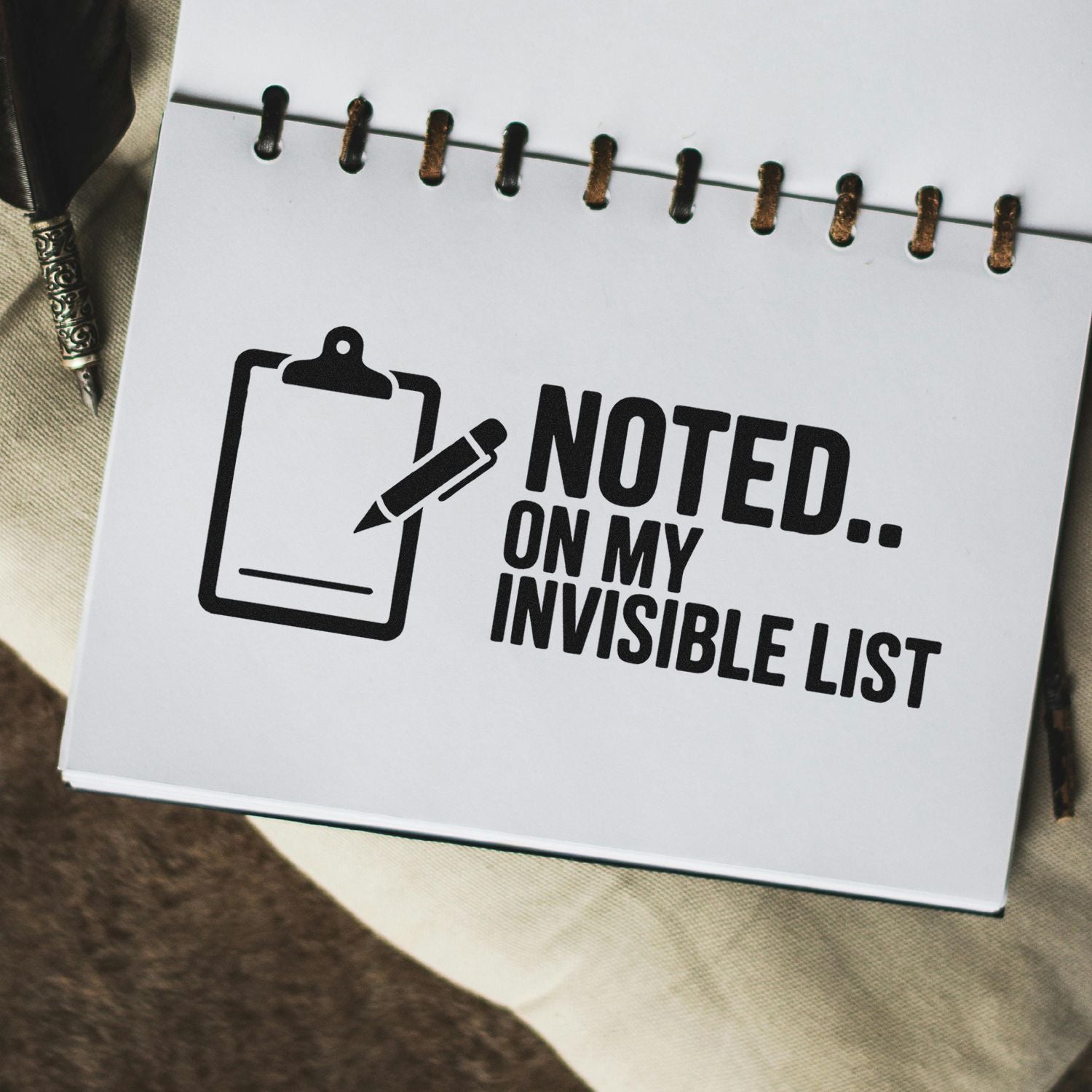 Black stamp seal on a white notepad, with clipboard icon and bold text reading Noted on my invisible list.