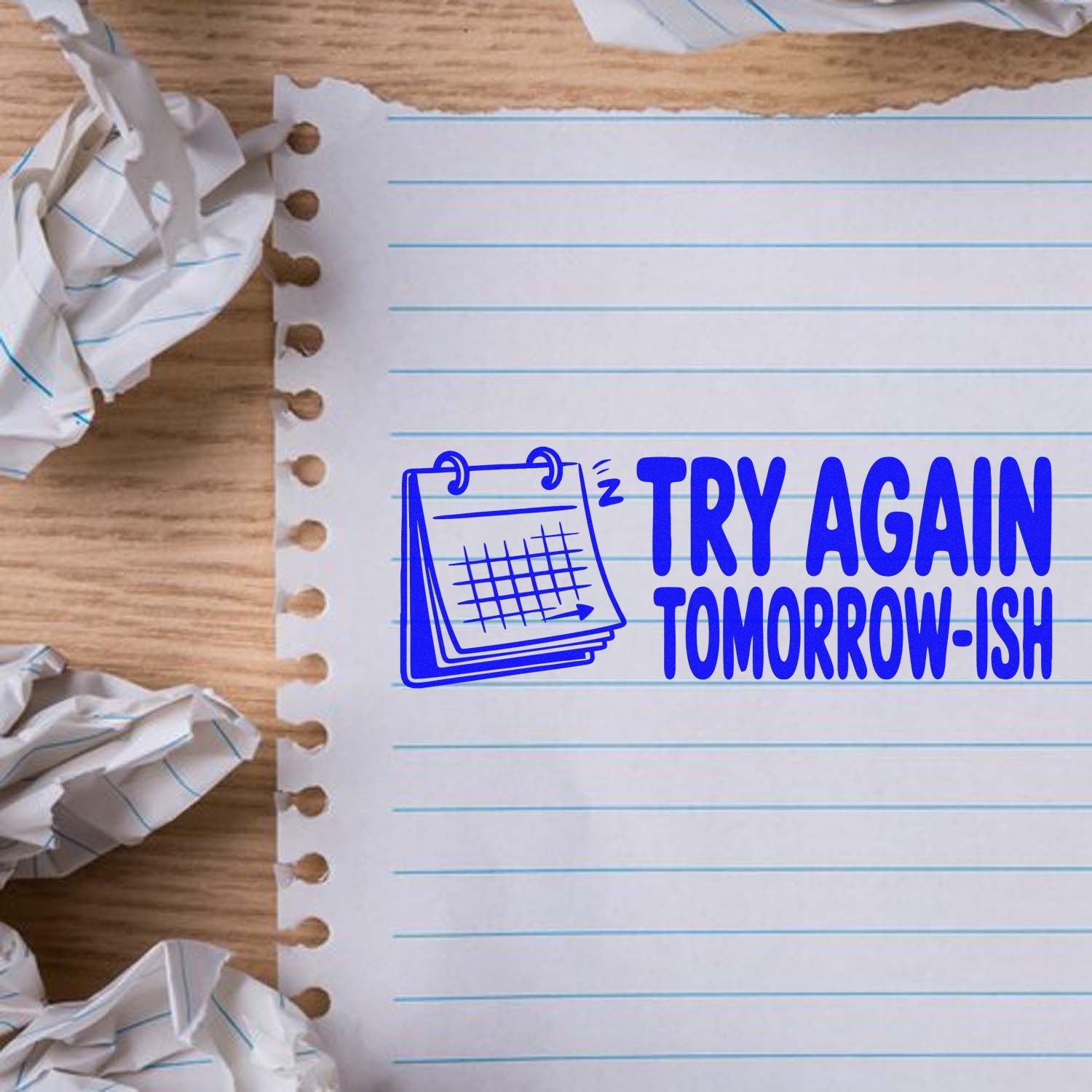 Blue stamp-style seal reading Try Again Tomorrow-ish on lined notebook paper with crumpled paper.