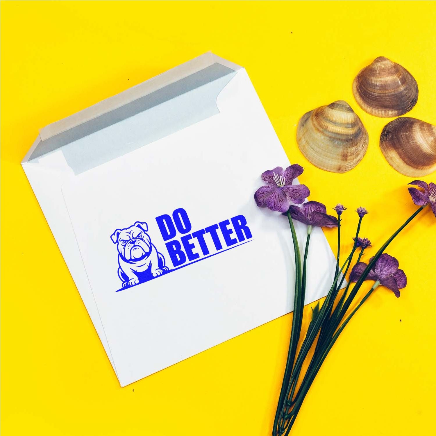 White custom stamp and seal envelope with blue bulldog DO BETTER logo on bright yellow, accented by purple flowers and seashells.