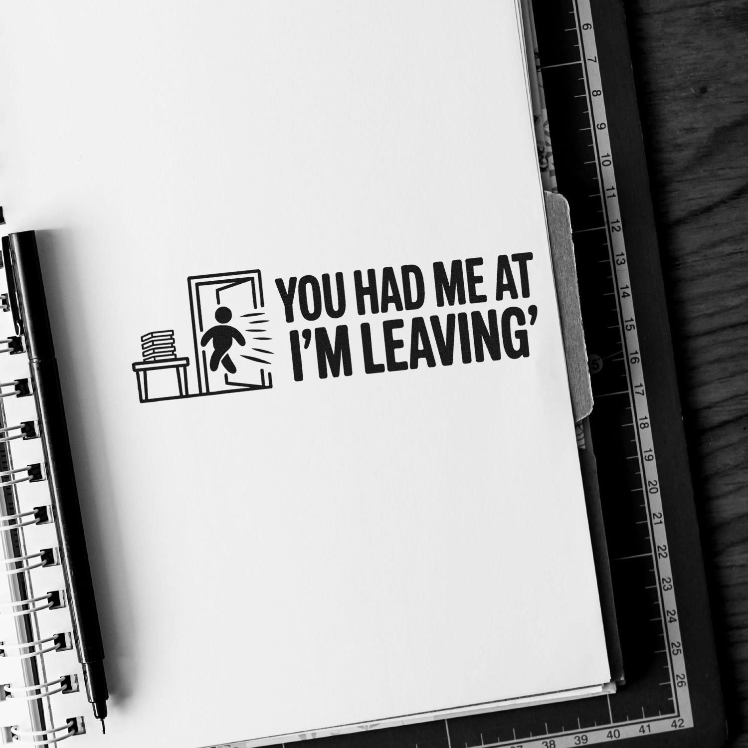 Black stamp and seal design on white notebook page reading YOU HAD ME AT IM LEAVING with exit icon.