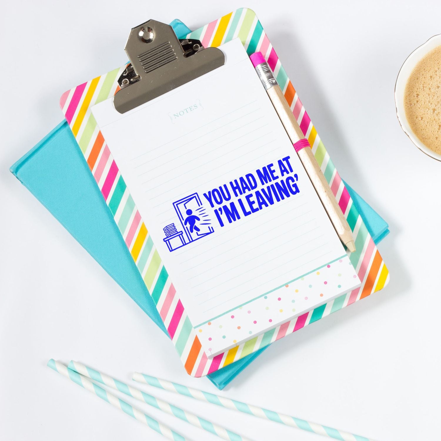 Colorful striped clipboard note pad with blue custom stamp and seal, pencil, and coffee cup.