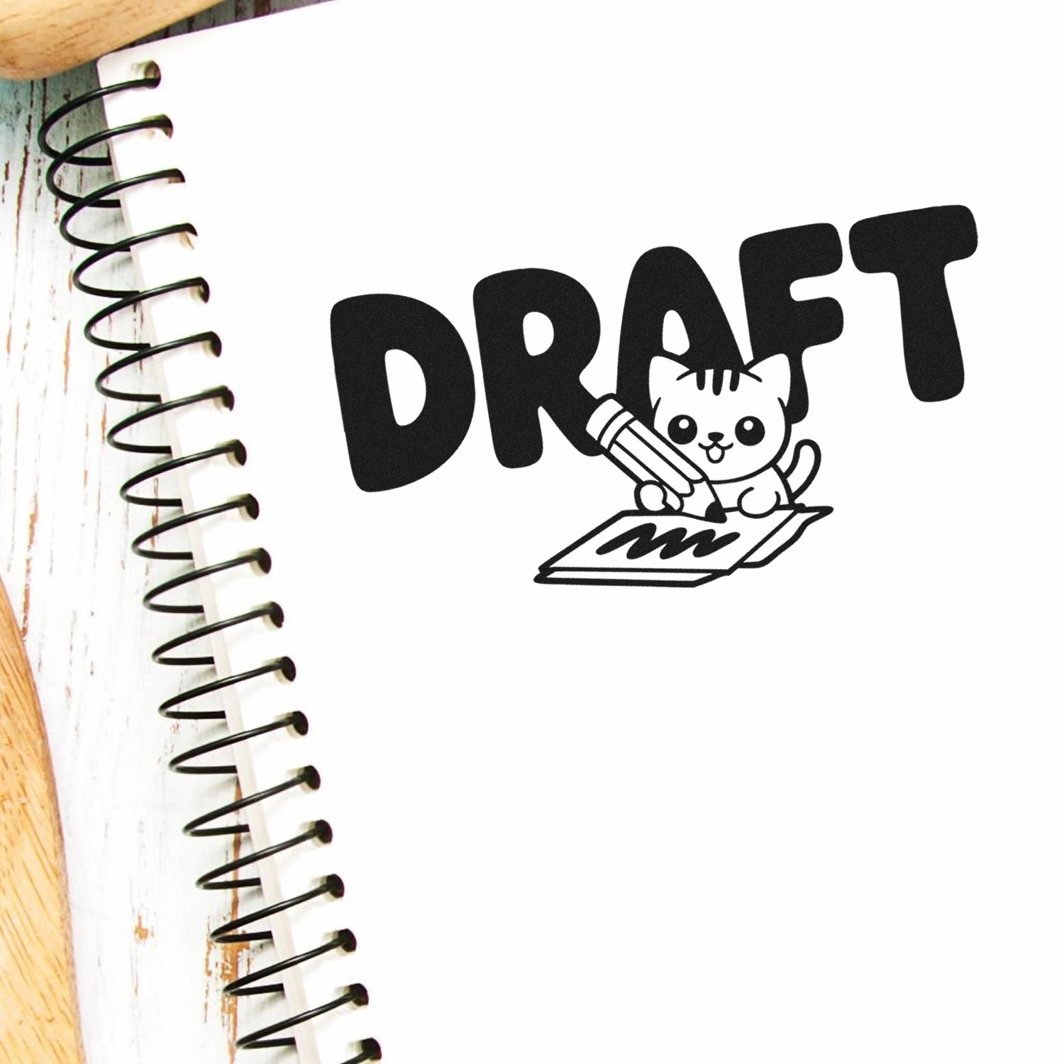 Black draft cat stamp with pencil on white spiral notebook, bold DRAFT text and seal-style graphic.