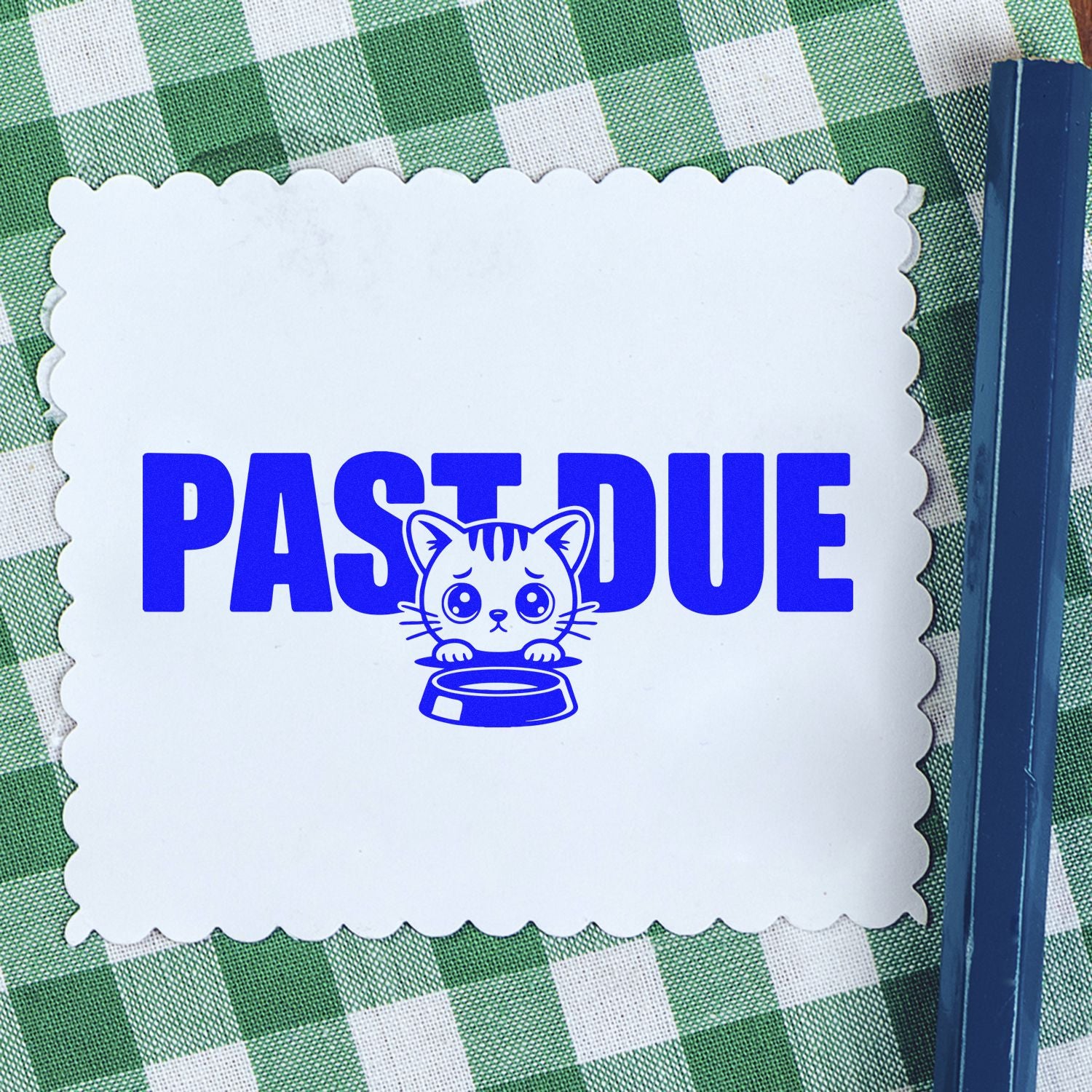 Blue PAST DUE cat stamp on a white scalloped seal, shown on green checkered fabric with a blue stamp tool.