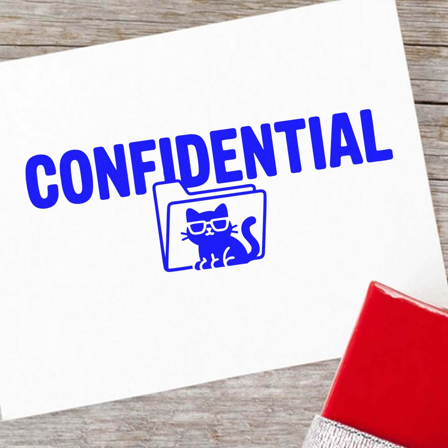 Blue confidential stamp with cat-in-folder seal on white paper, beside a red stamp pad on a wood background.