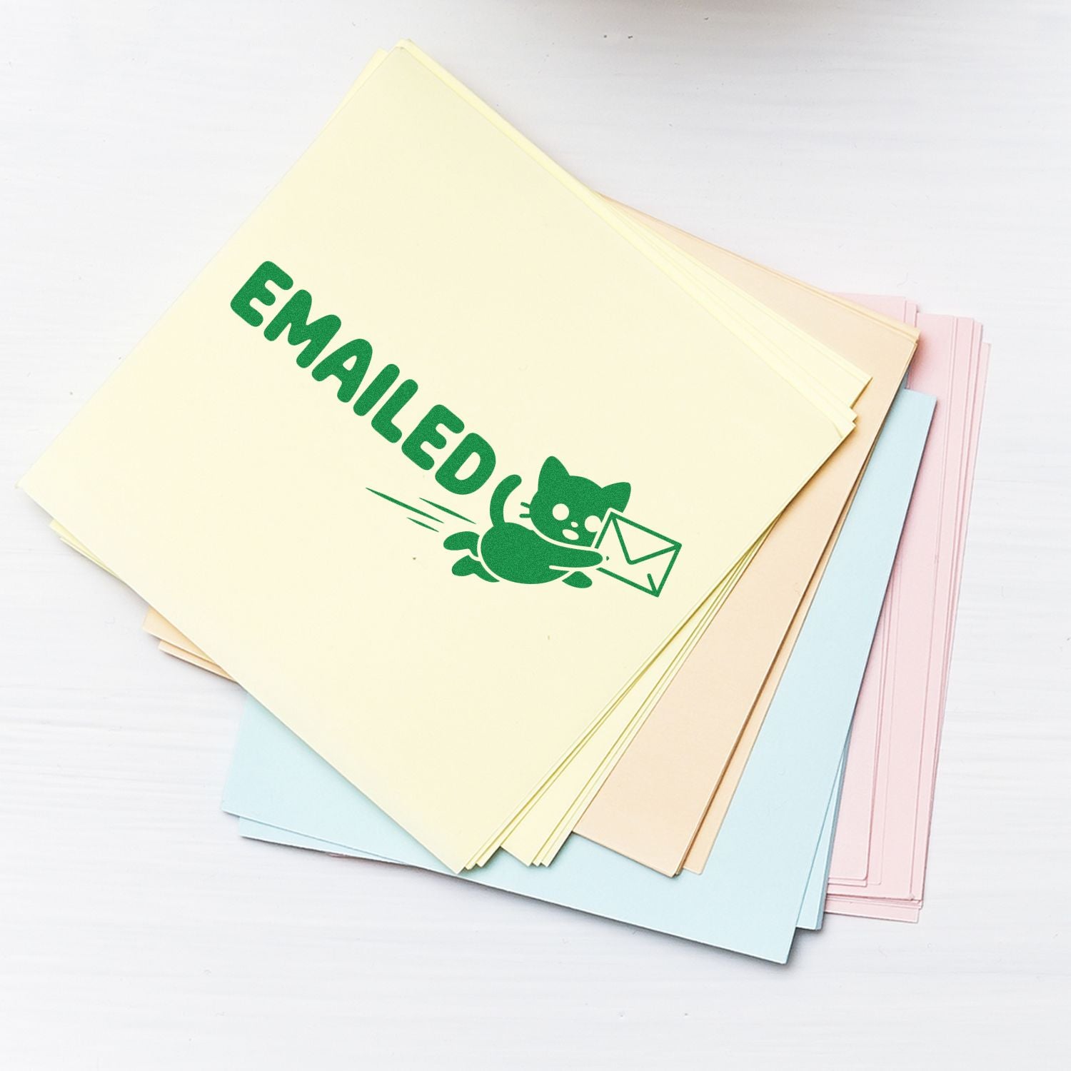 Pastel stamp and seal sheets with green EMAILED cat-envelope design on cream paper, stacked over blue, pink, and beige sheets.