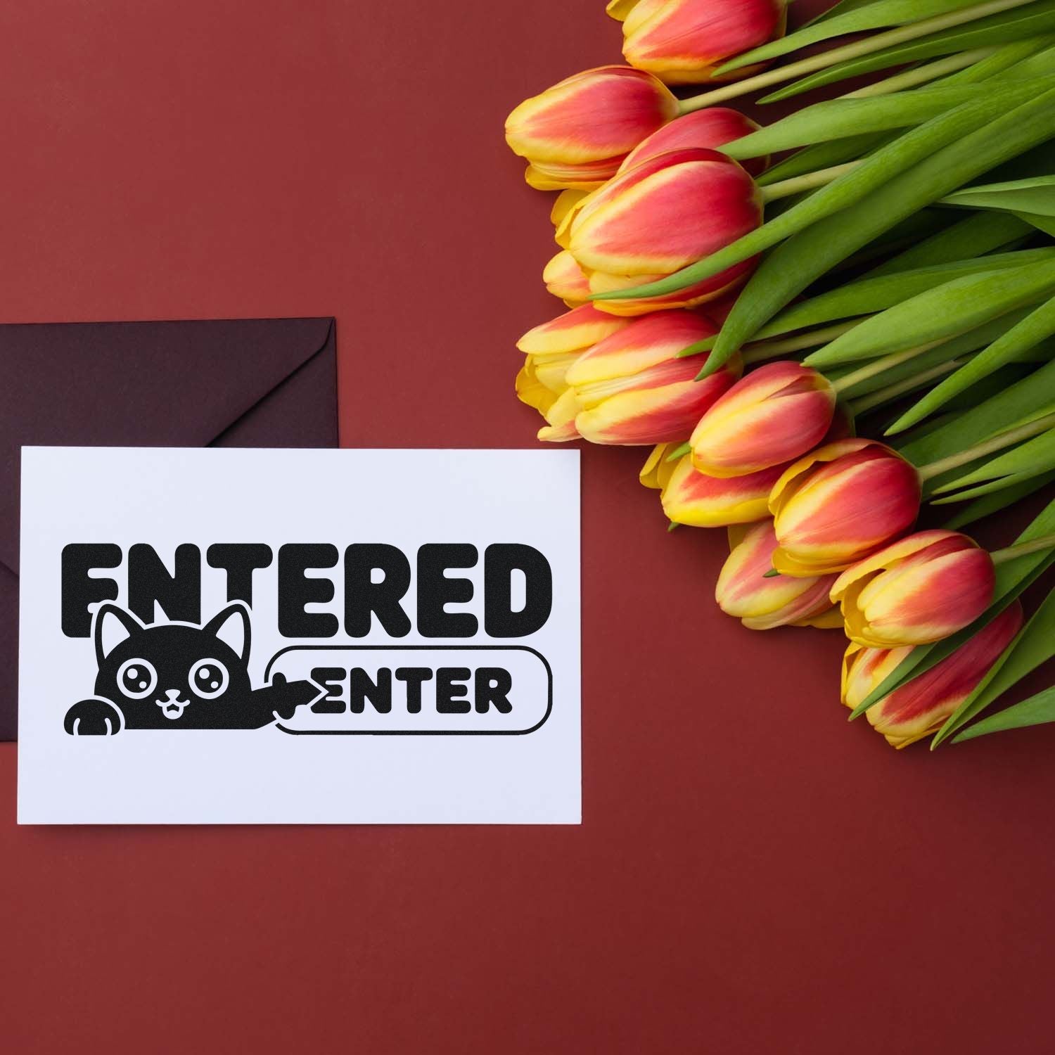 Black ENTERED stamp and seal with cat graphic on white card beside pink-yellow tulips on a burgundy background.