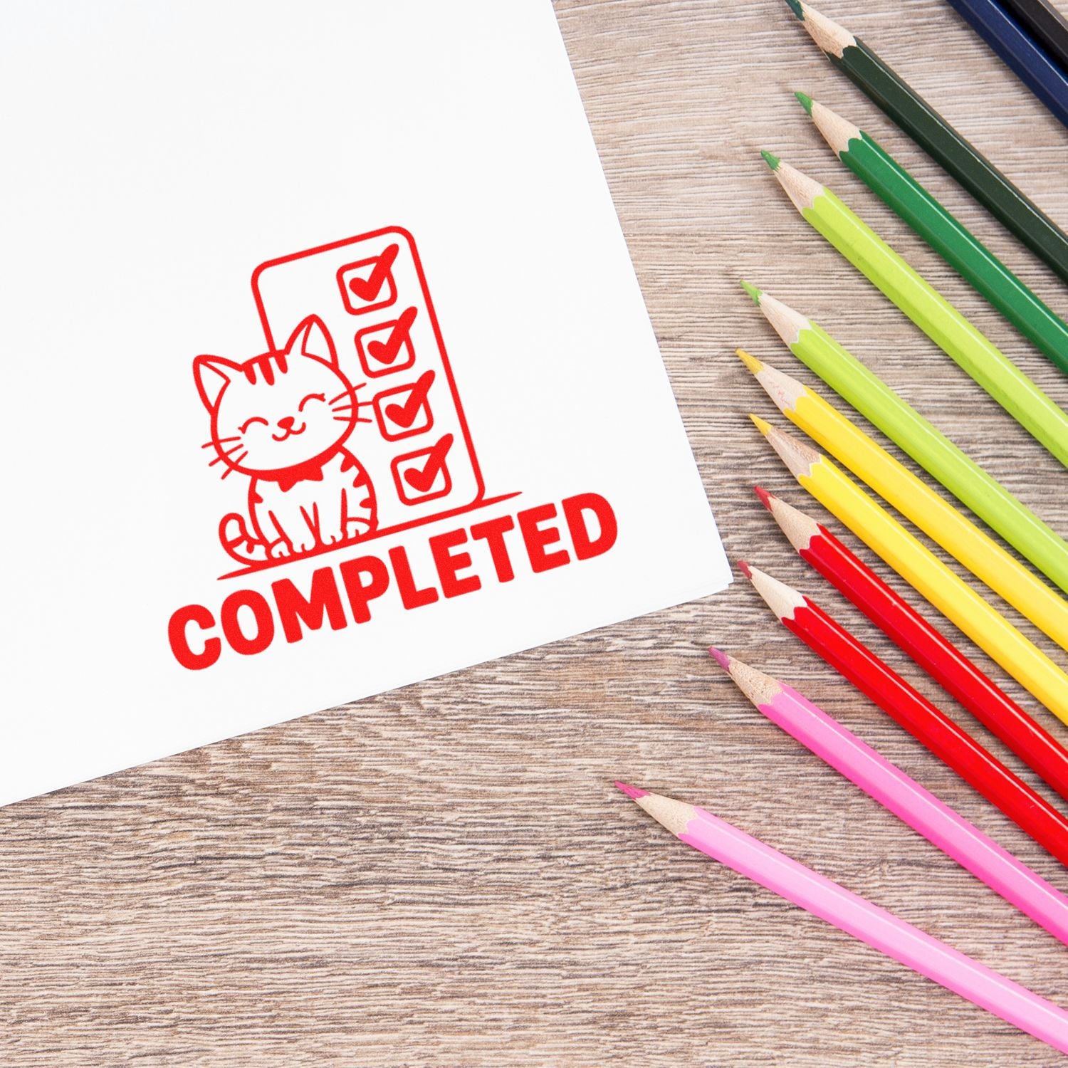 Red completed stamp seal with cat checklist beside colorful pencils on wood desk