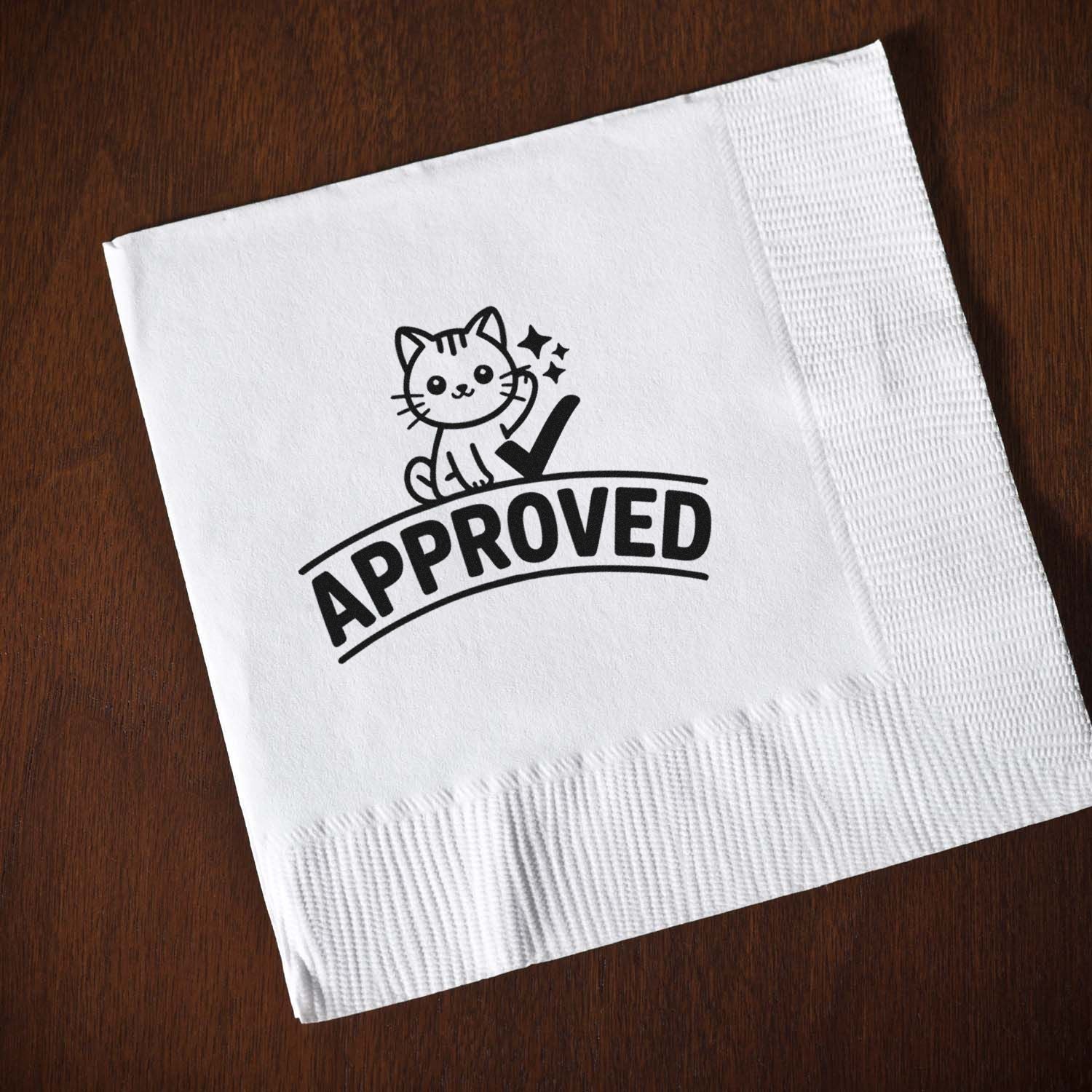 White napkin seal stamp with black cat, checkmark, and APPROVED text on dark wood.