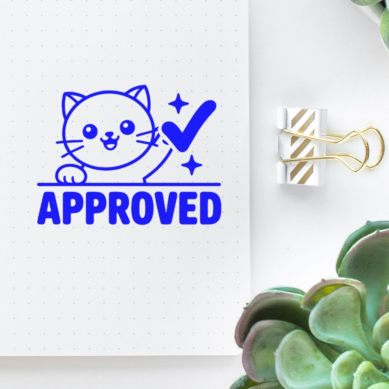 Blue cat APPROVED stamp with check mark on dotted notebook, beside gold striped paper clip seal