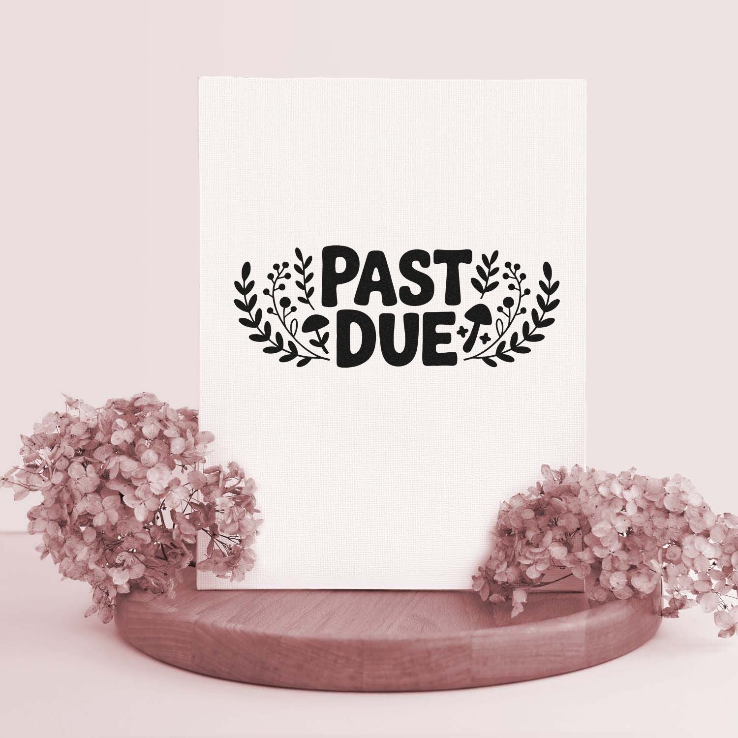 White stamp and seal display with black PAST DUE floral wreath, blush pink flowers, and a wooden base.