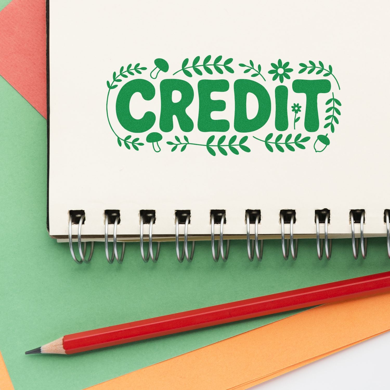Green CREDIT stamp-style seal design on a spiral notebook, with leaf border, red pencil, and pastel paper backgrounds.