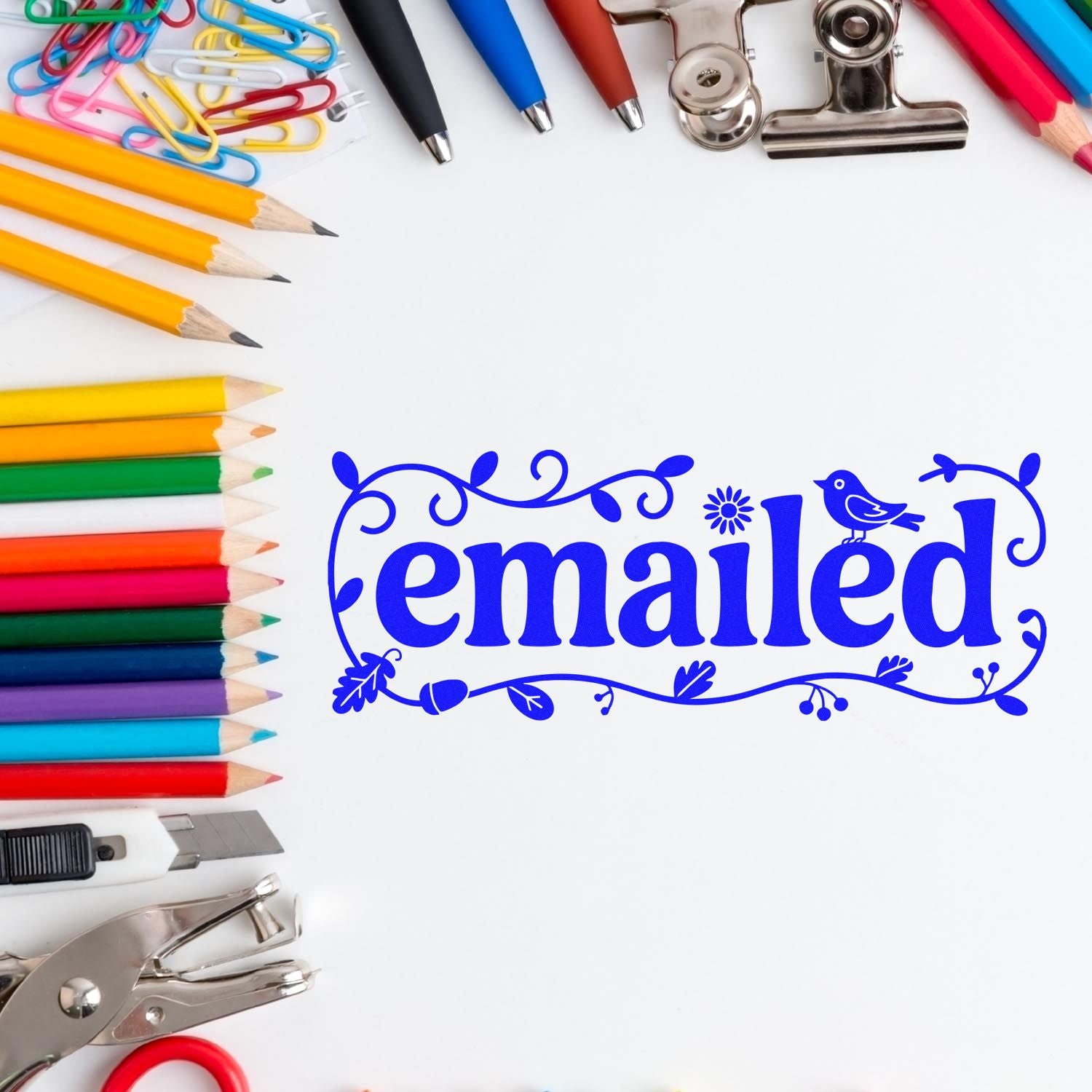 Blue emailed stamp seal surrounded by colorful pencils, paper clips, pens, and metal binder clips on white.