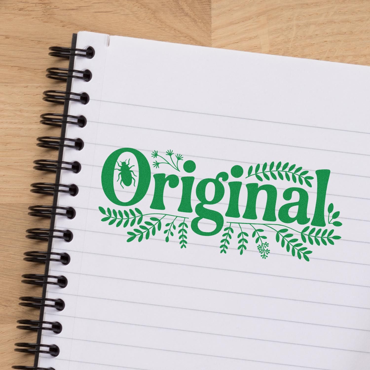 Green original stamp seal with leaf accents and insect motif on a white spiral notebook