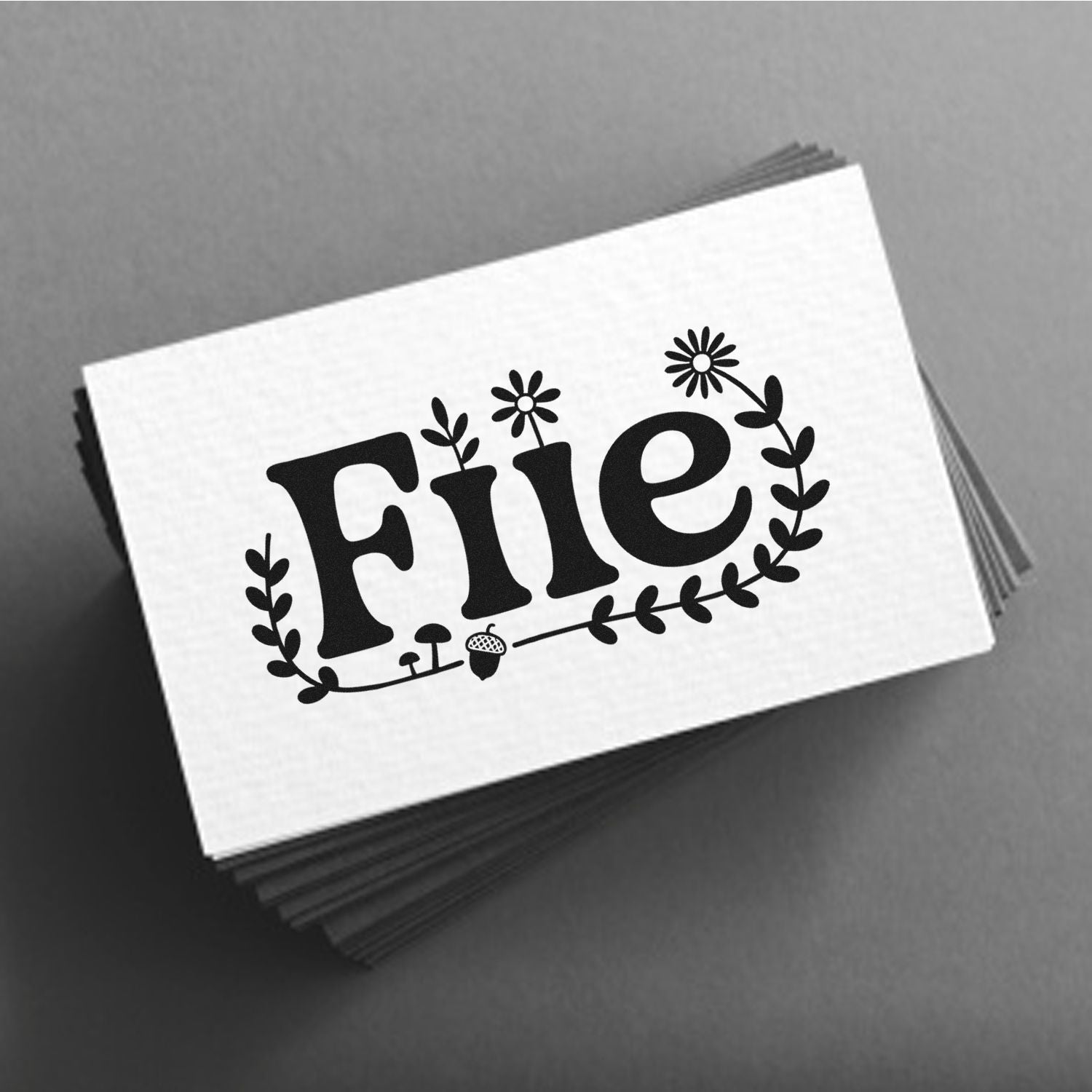 Black floral stamp seal design on stacked white cards against a gray background.