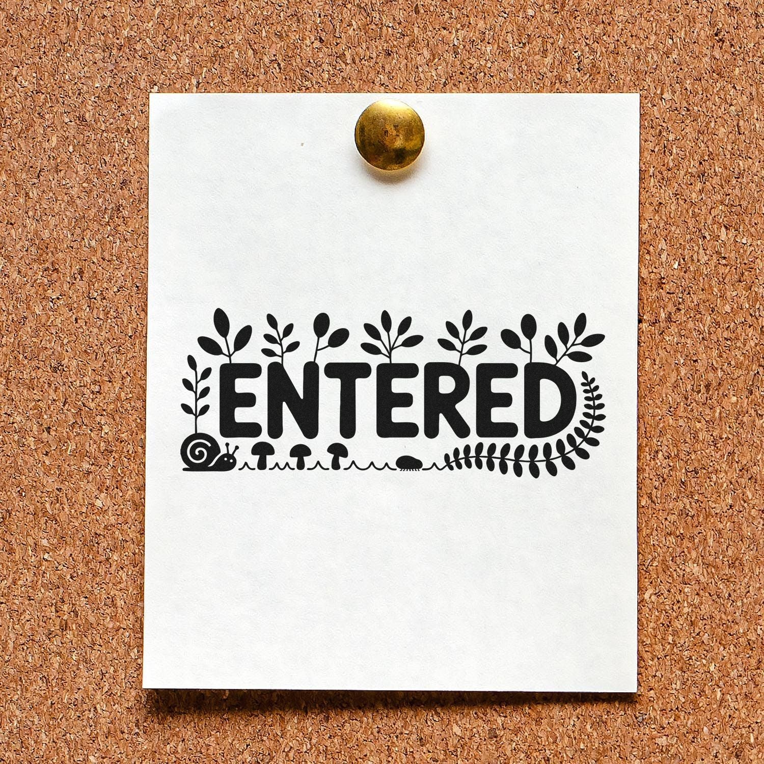 White card with black ENTERED stamp, botanical leaves, snail and mushrooms, pinned by brass tack on corkboard.