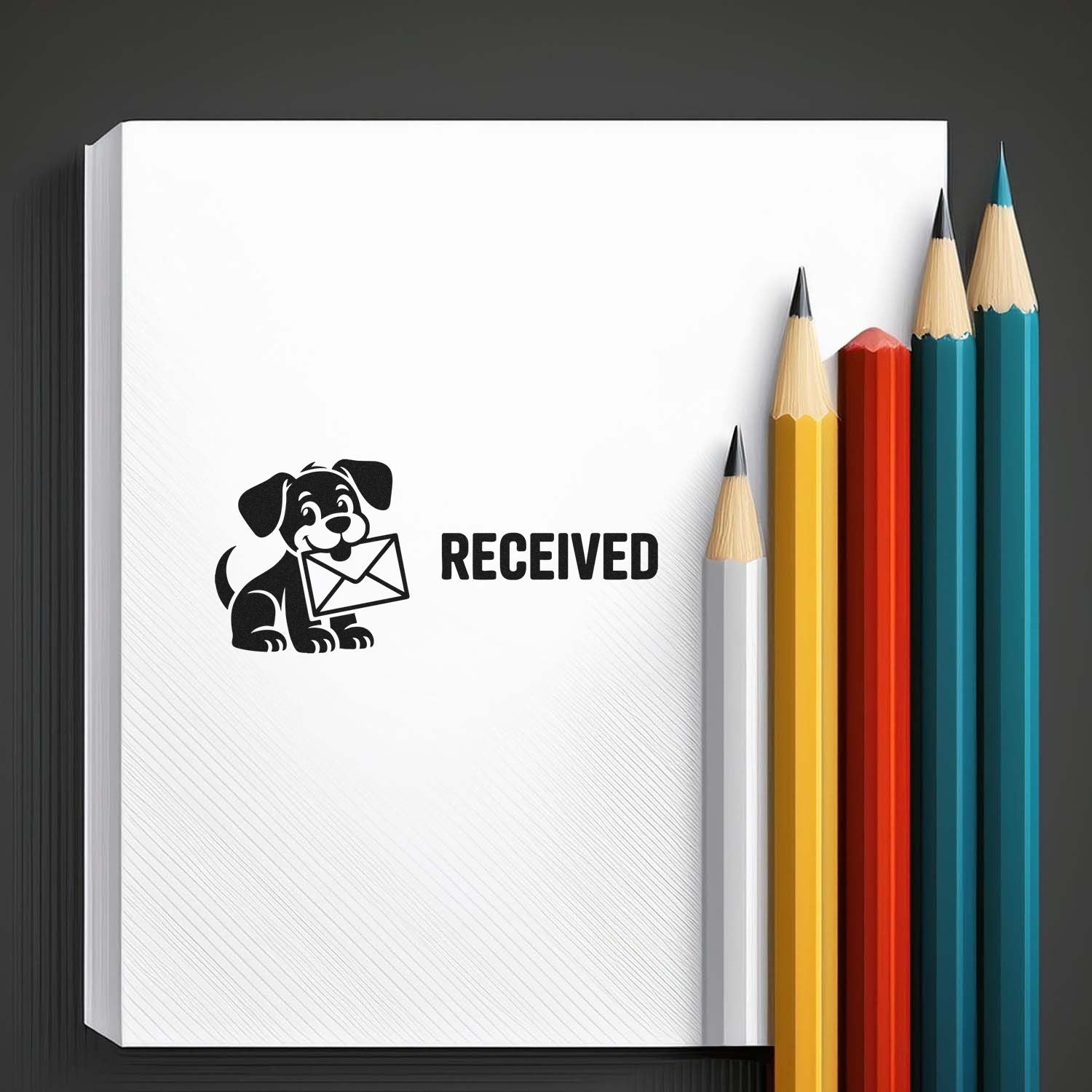 White notebook with black RECEIVED rubber stamp showing dog and envelope, beside yellow, red, teal and blue pencils.