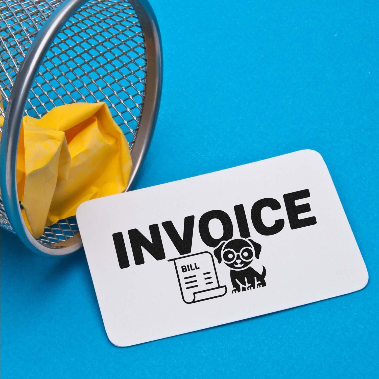White invoice stamp and seal product with black bill icon and dog, beside a metal mesh tray, yellow paper, on bright blue background.