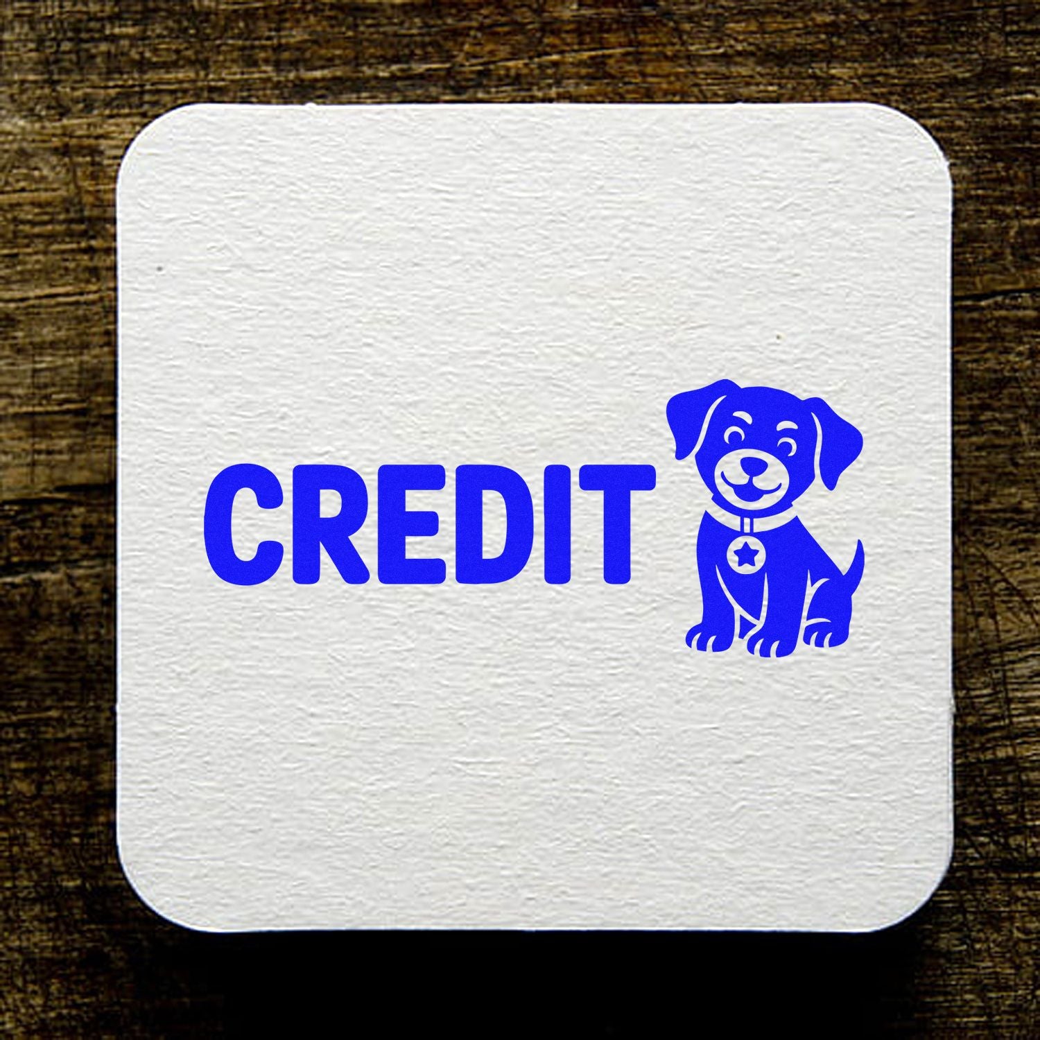 Blue CREDIT dog stamp and seal design on a white textured square seal against a dark wood background.