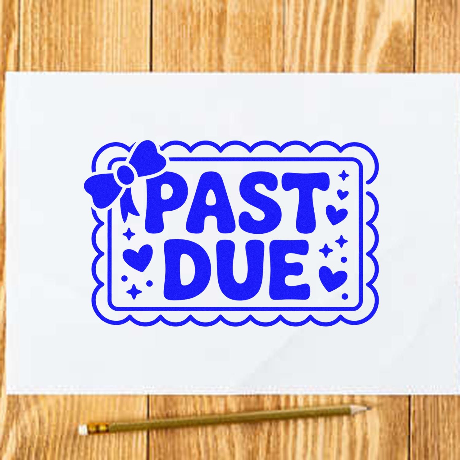 Blue pastel-style PAST DUE stamp seal with hearts and bow on white paper over a wood table.
