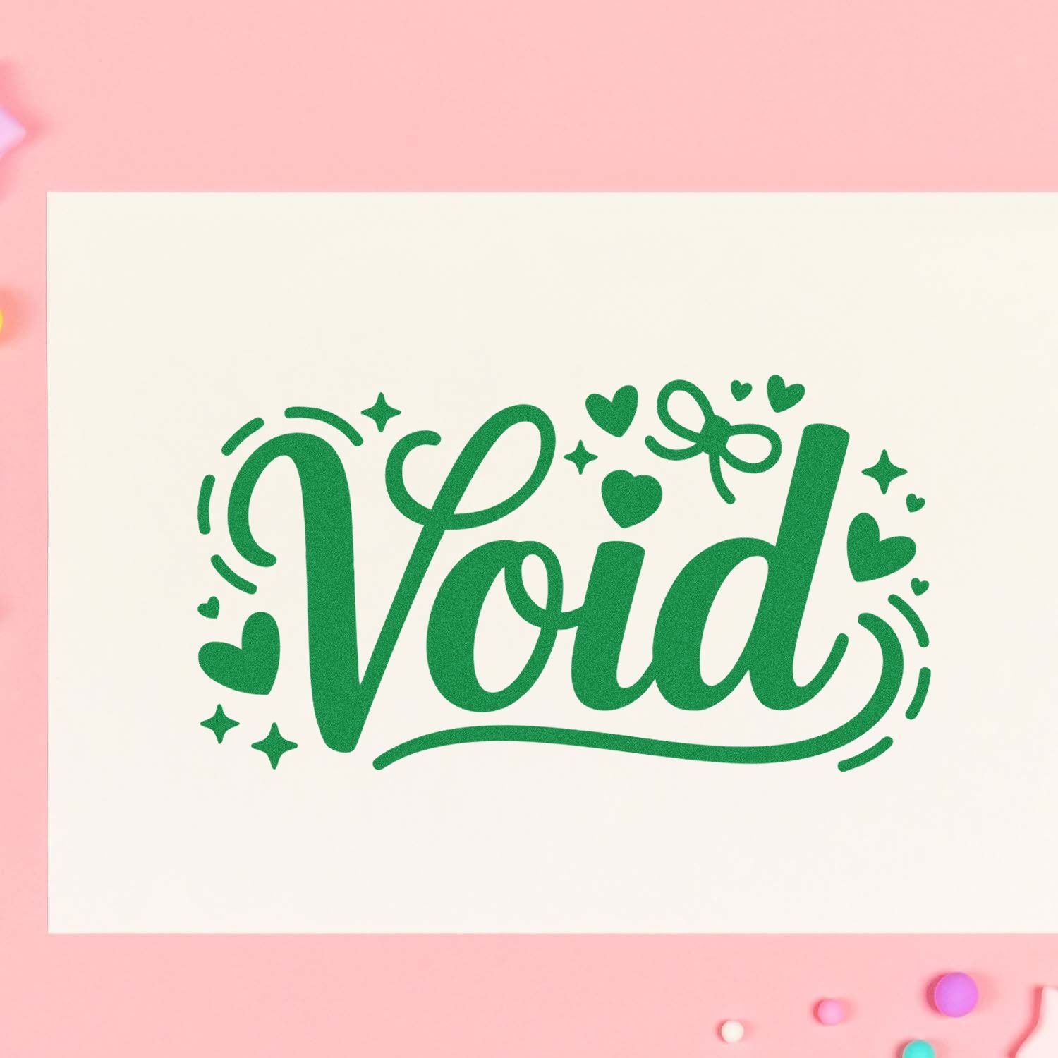 Green Void stamp and seal design with hearts and stars on a white card, set against a pink background.