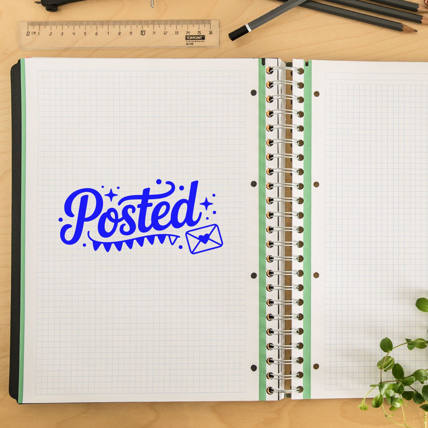 Blue Posted rubber stamp and seal on open graph notebook, with spiral binding, ruler, pencils, and green plant.