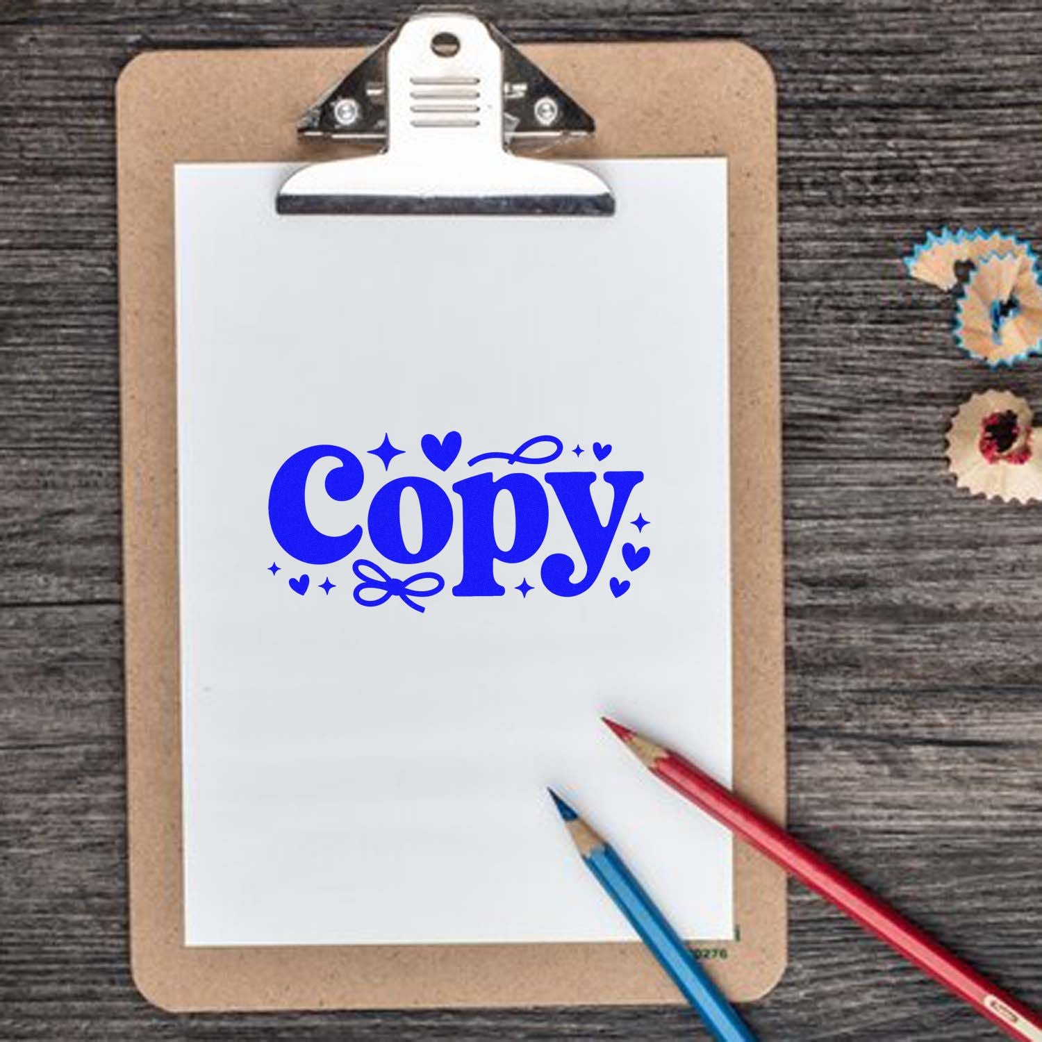 Clipboard with white paper and blue Copy stamp, red and blue pencils, and small stamp and seal product samples.