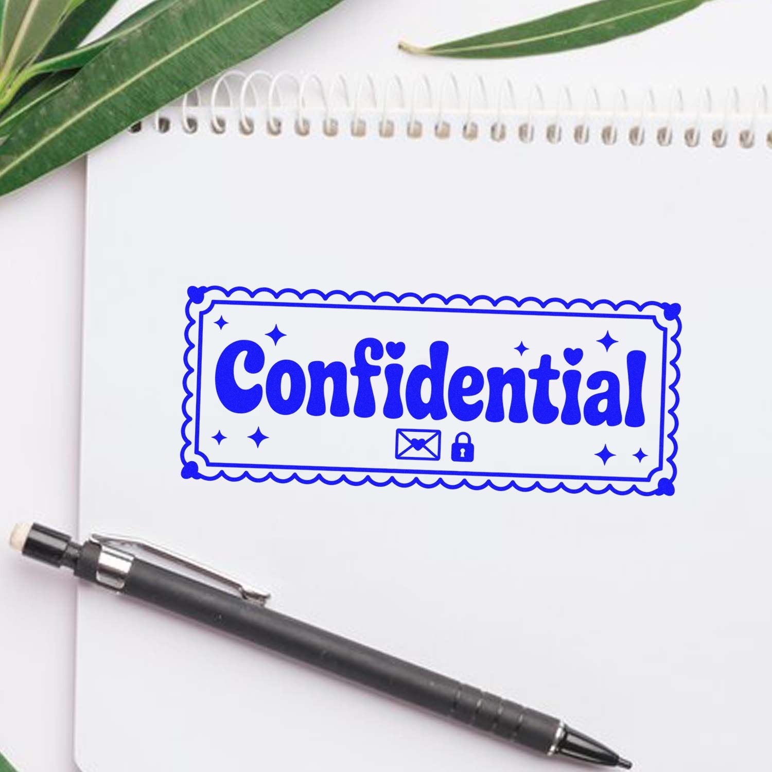 Blue confidential stamp seal on white spiral notebook, with black pen and green leaves.