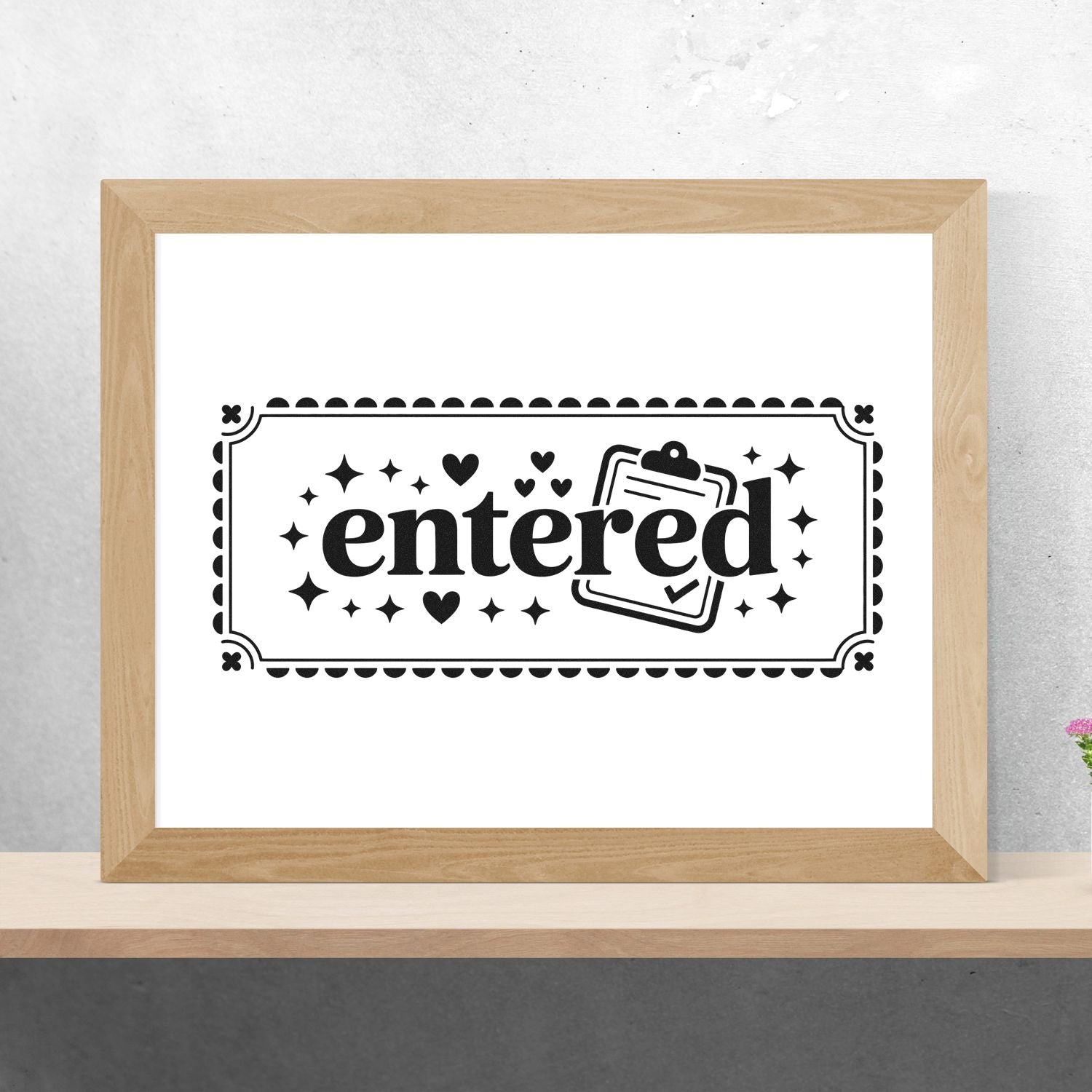 Black entered stamp seal with hearts, stars and clipboard icon in a light wood frame on a white background.