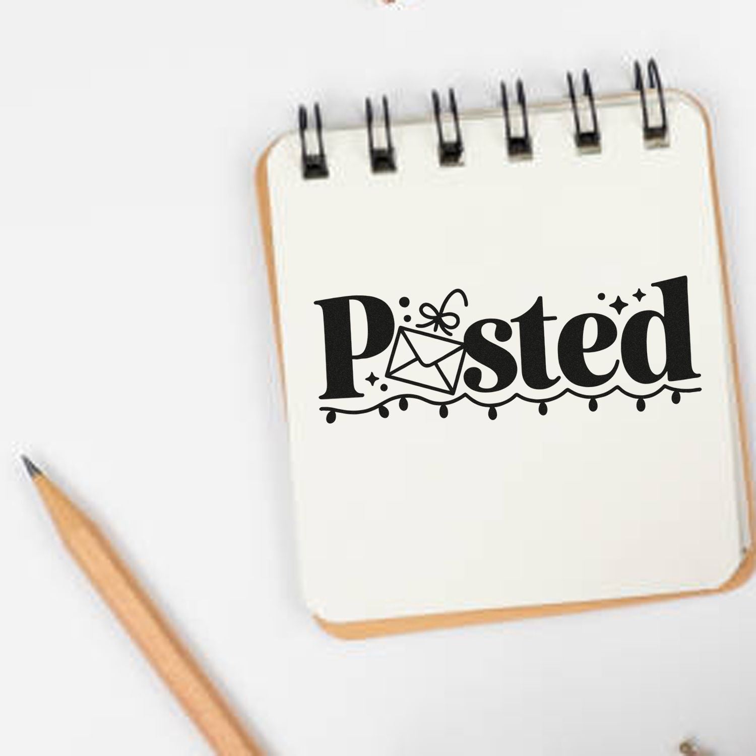 Black decorative Posted stamp seal with envelope and string lights on a cream notebook, beside a wooden pencil.