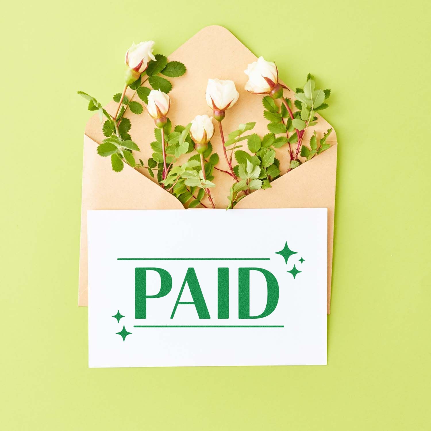 Green PAID stamp seal on white card over kraft envelope with white roses and green leaves on light green background.