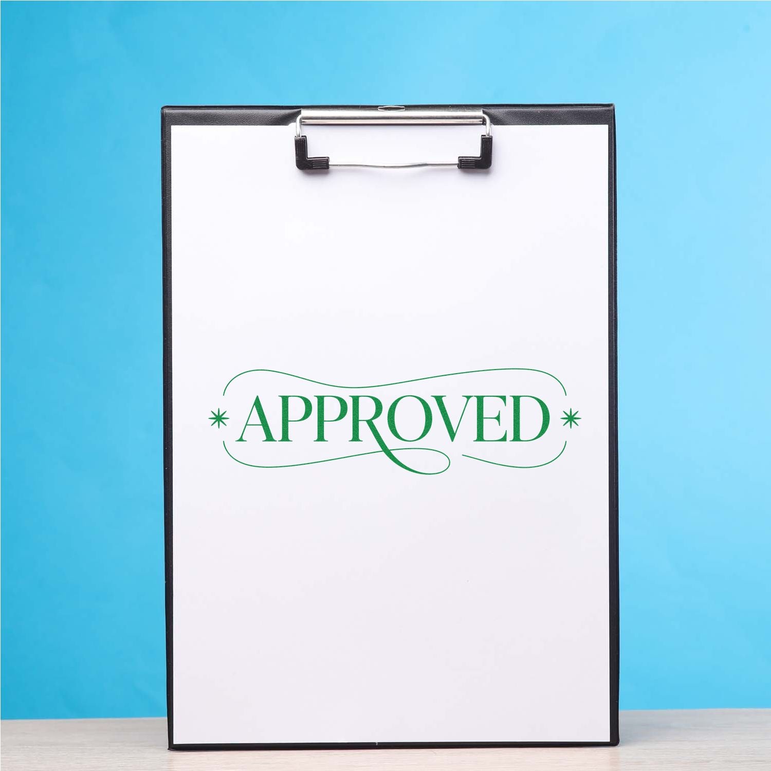 Clipboard with green APPROVED stamp and decorative seal on white paper, black frame against a blue background.