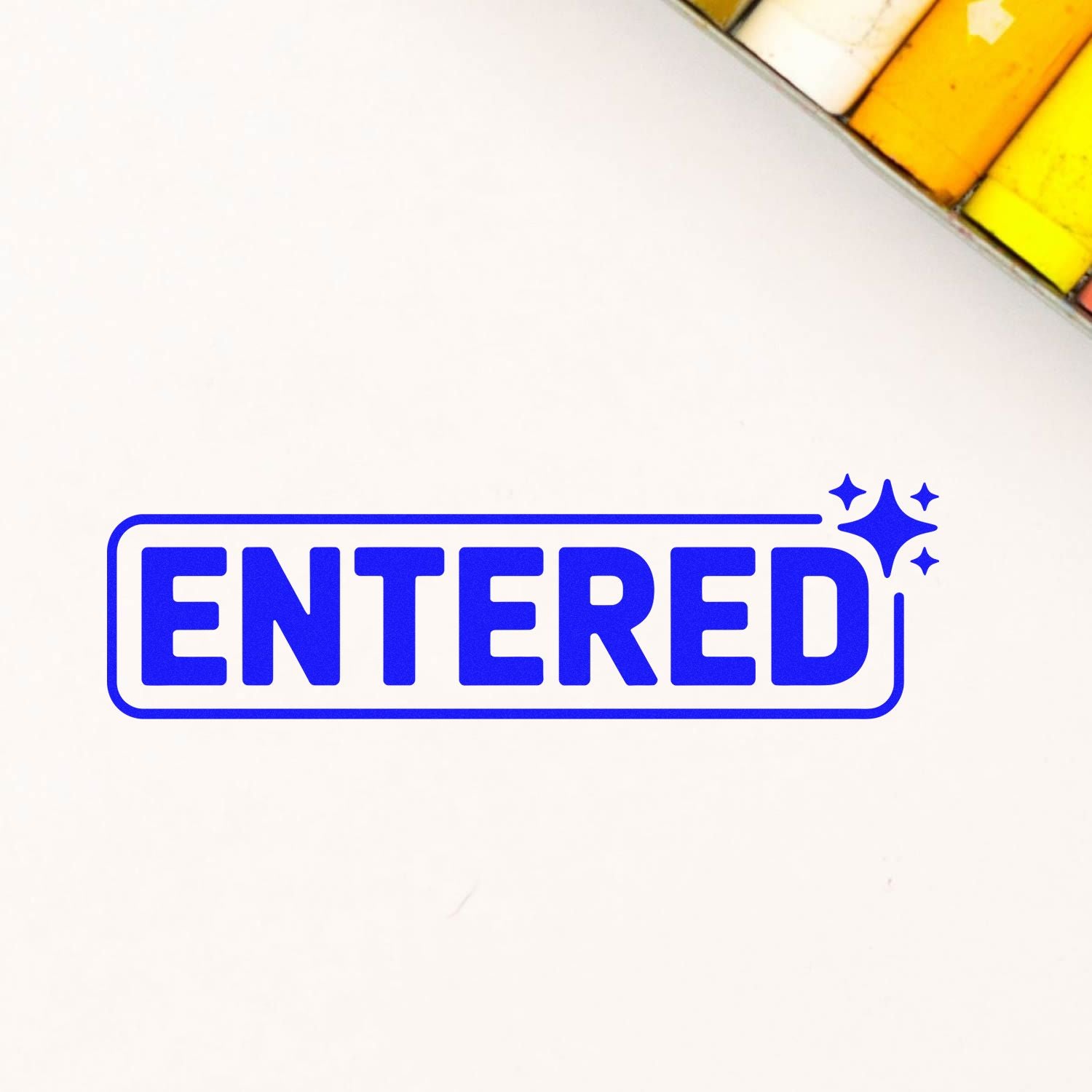 Blue ENTERED rubber stamp seal with sparkle icons on a white background, with yellow stamp pads in the corner.