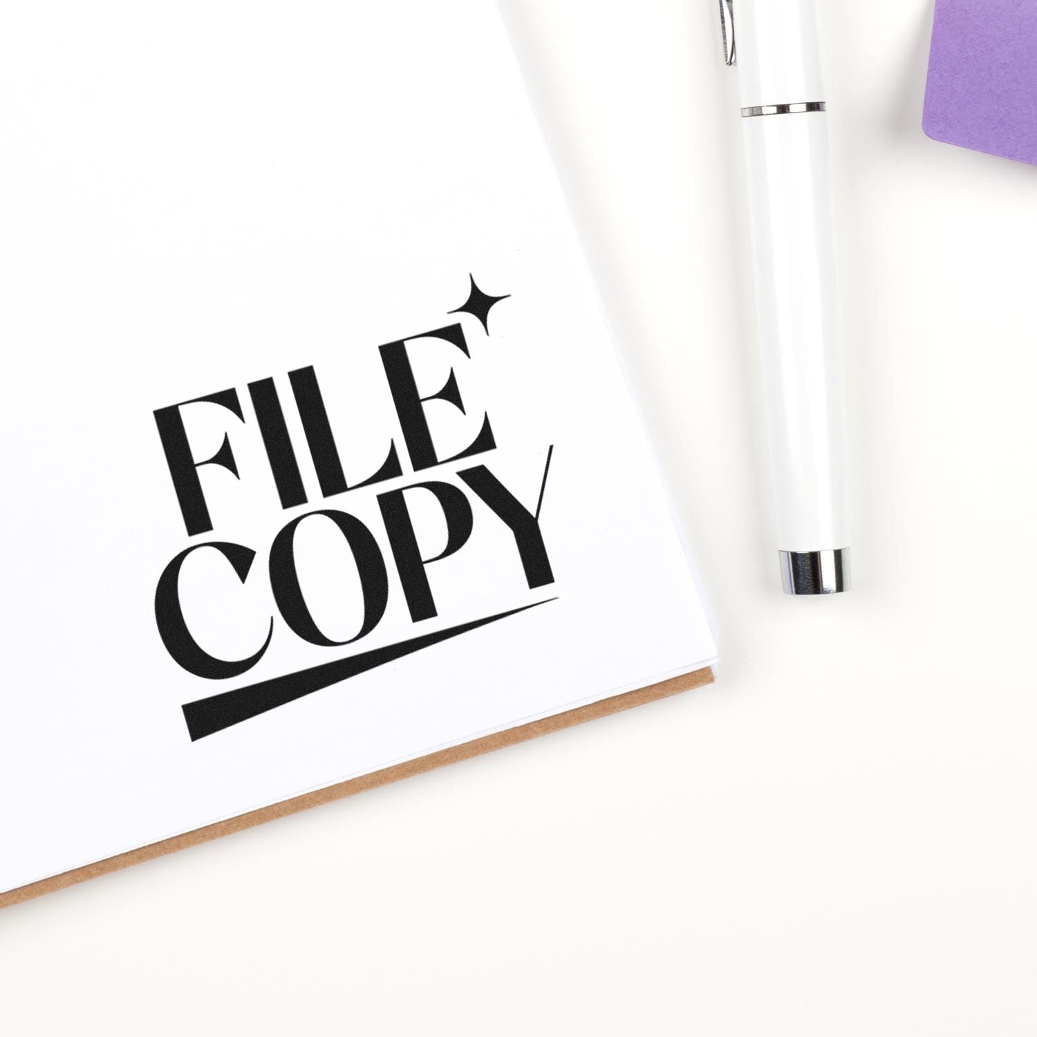 Black FILE COPY stamp seal on white paper beside a white pen and purple folder, showcasing office stamp products.