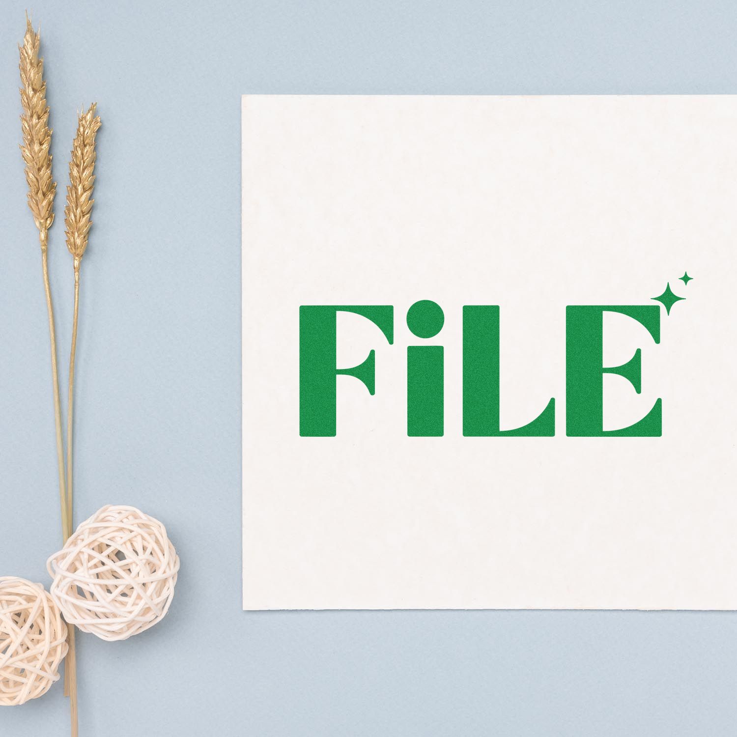 Green FILE stamp seal on white card with sparkles, set on pale blue background with wheat stems and wicker balls.
