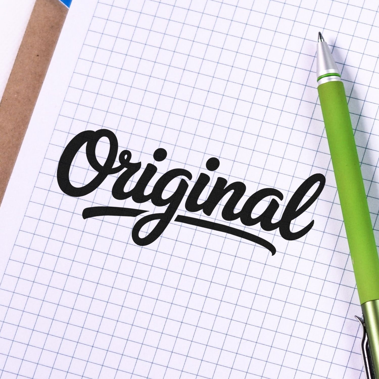 Black "Original" stamp seal on grid paper beside a green pen