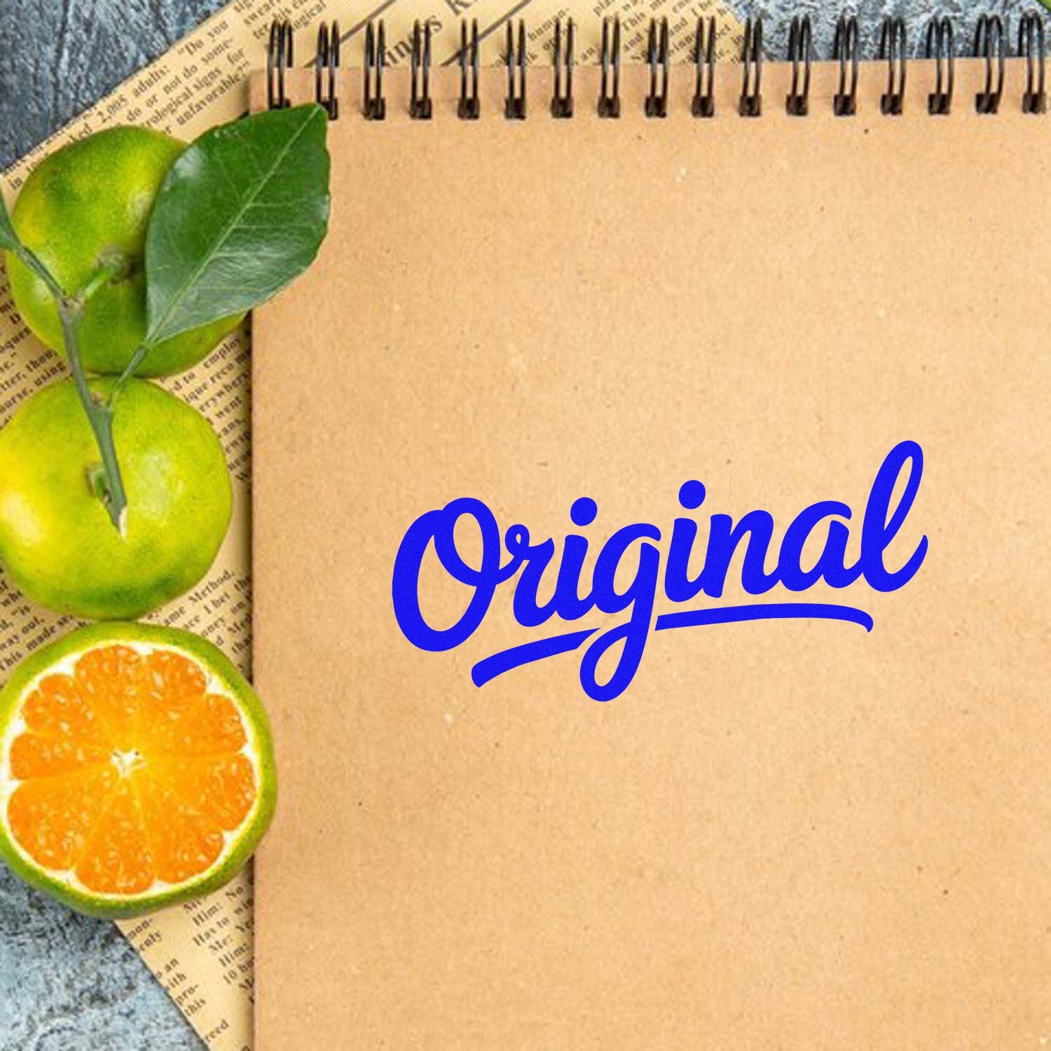 Blue Original stamp on kraft notebook with green leaves and sliced citrus seal accents