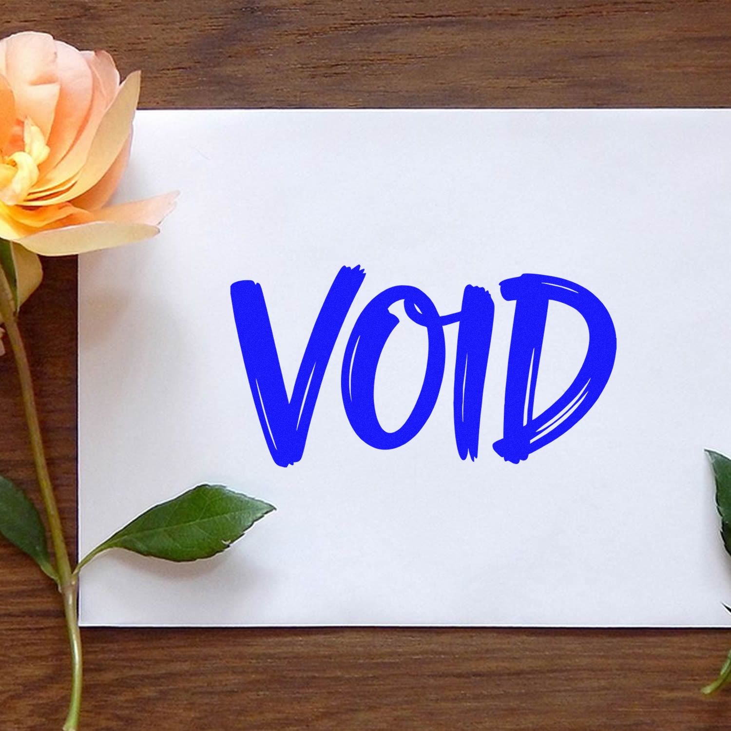 Blue VOID security stamp on white card, framed by peach flower and green leaves on a wooden background.