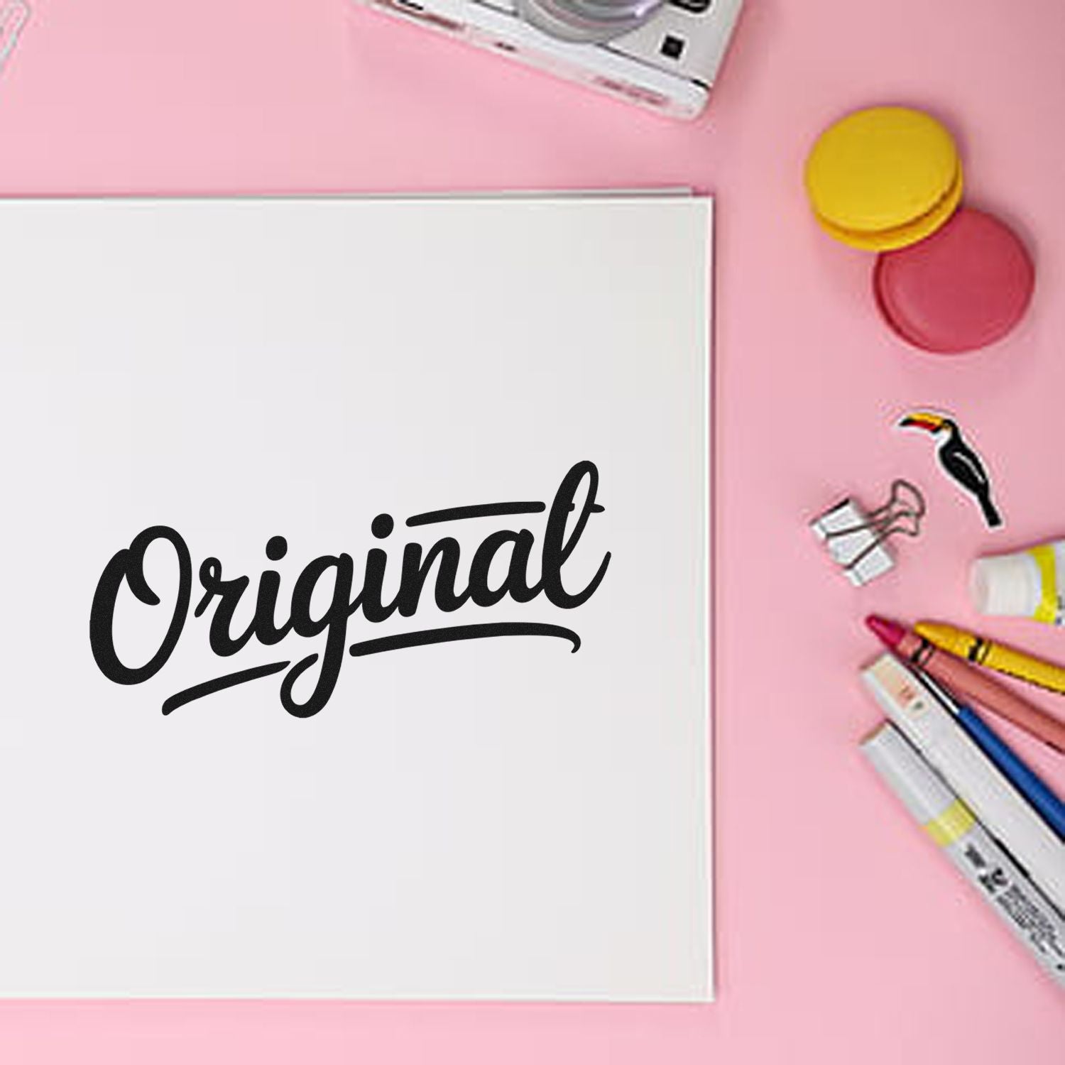 White notebook with black Original script, pink background, and yellow-pink stamp and seal products with colorful markers.