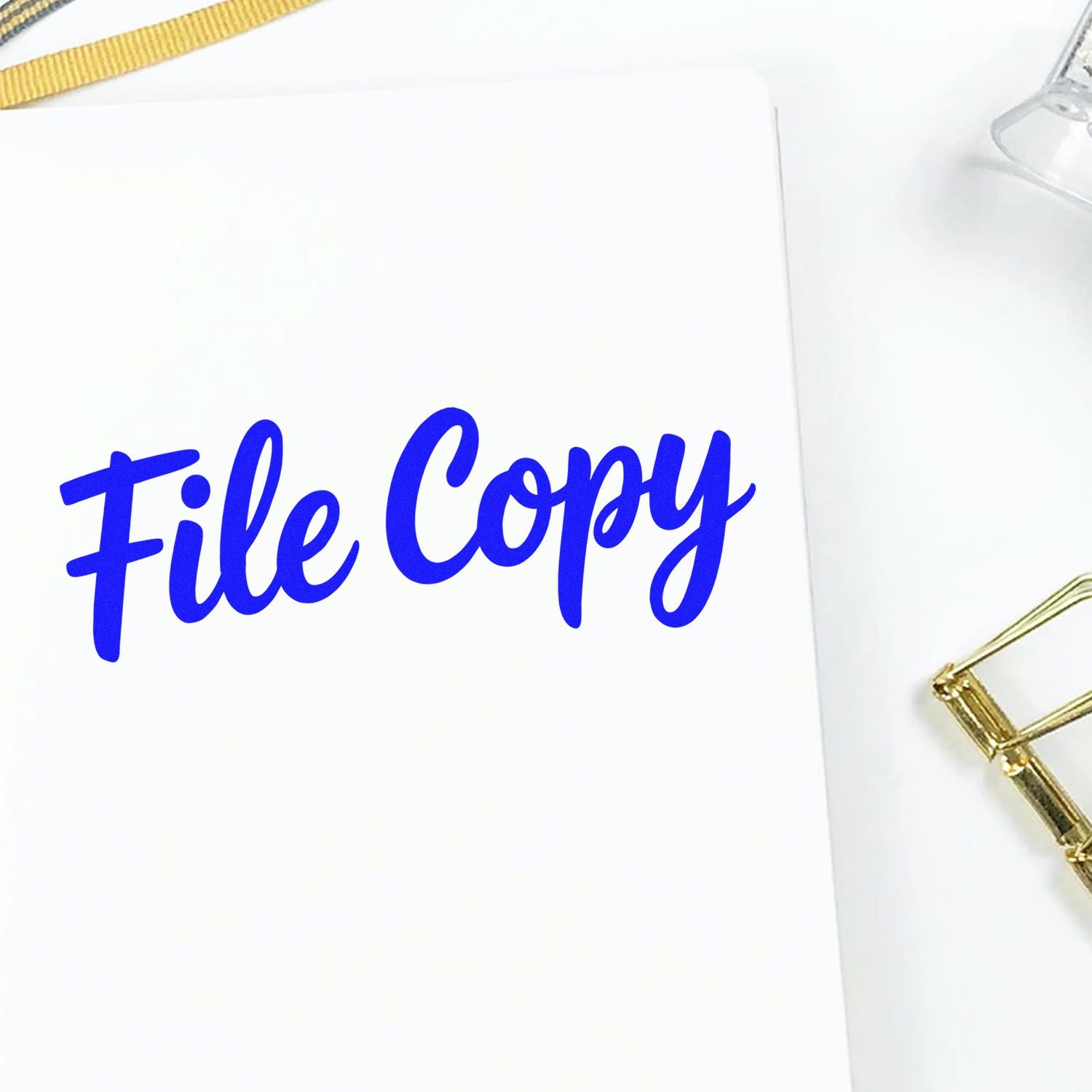 Blue File Copy stamp on white paper, with gold binder clip and ribbon accents