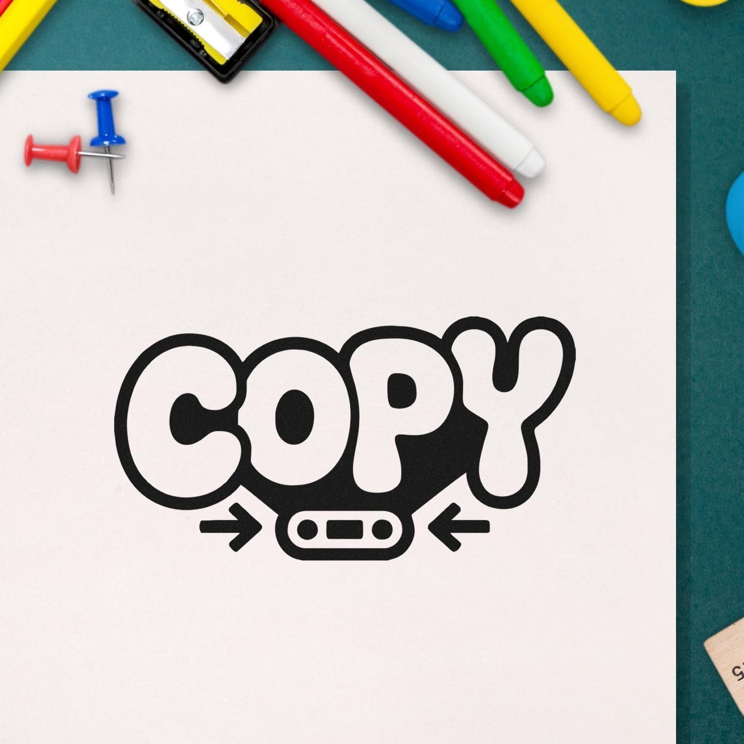 Black COPY self-inking stamp and seal on white paper, framed by colorful pens and push pins.