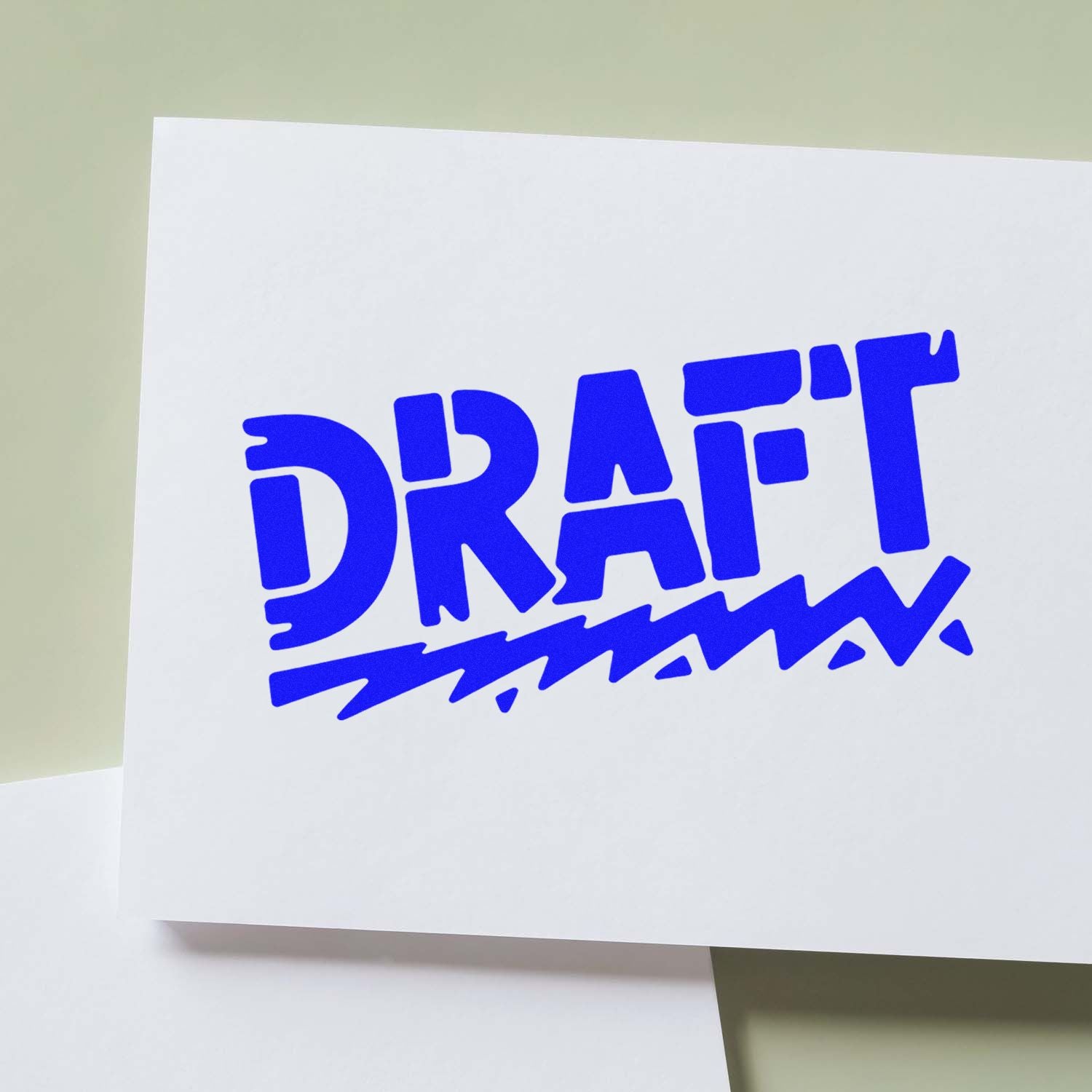 Blue DRAFT rubber stamp seal on white paper, angled over a pale green background.