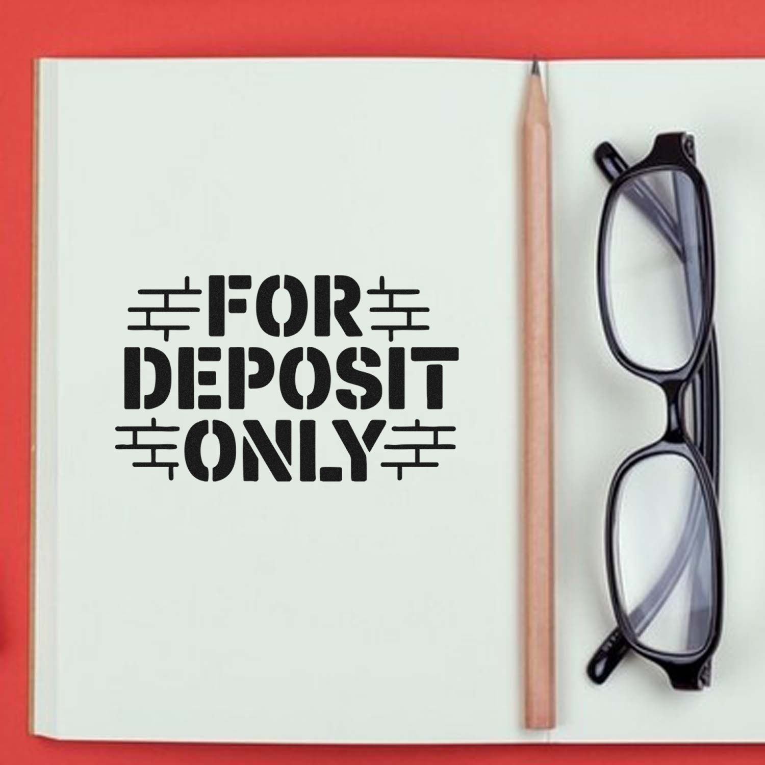 Black FOR DEPOSIT ONLY stamp and seal on a white notebook page with pencil and black eyeglasses on a red background.