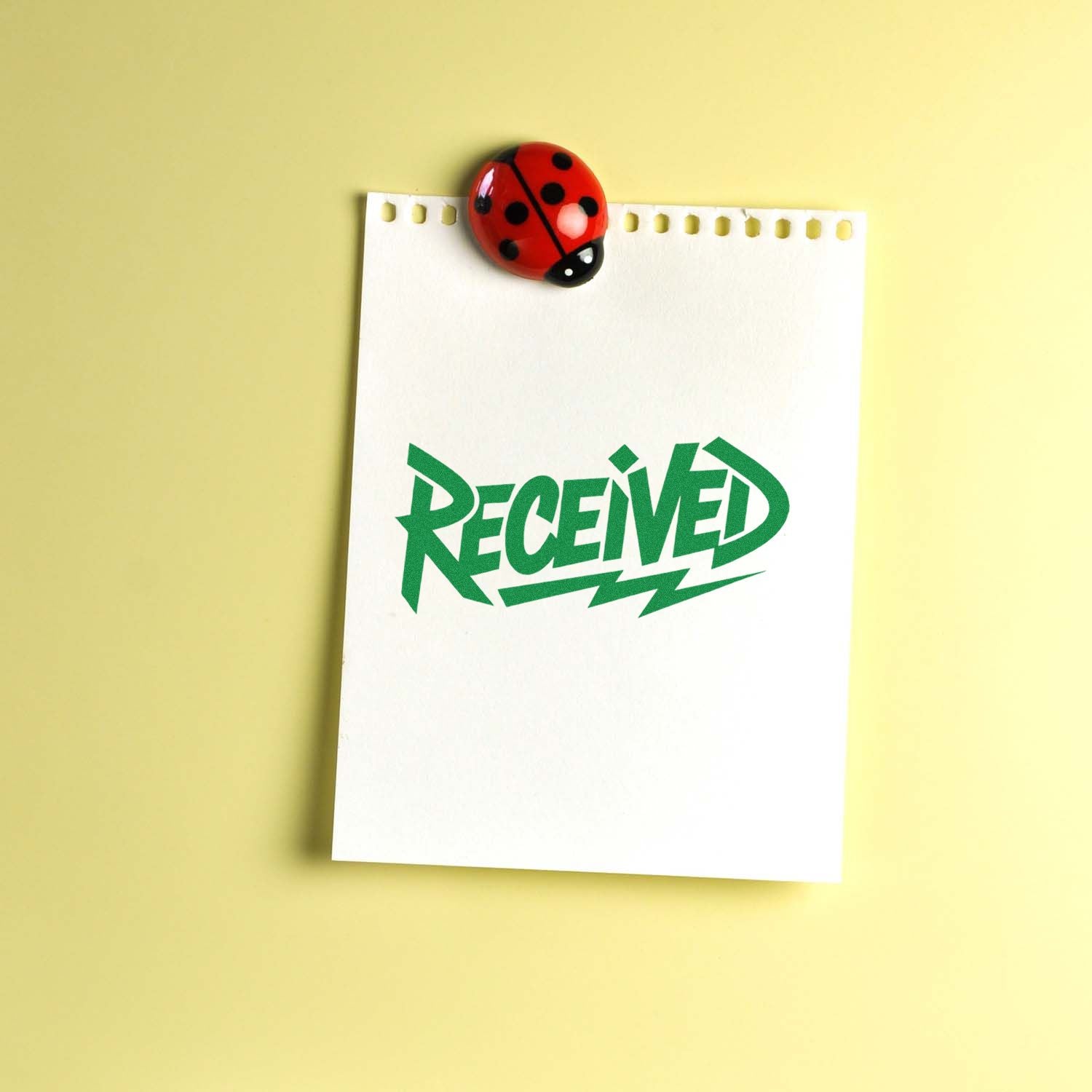 White paper with green RECEIVED stamp and red ladybug seal on a pale yellow background.